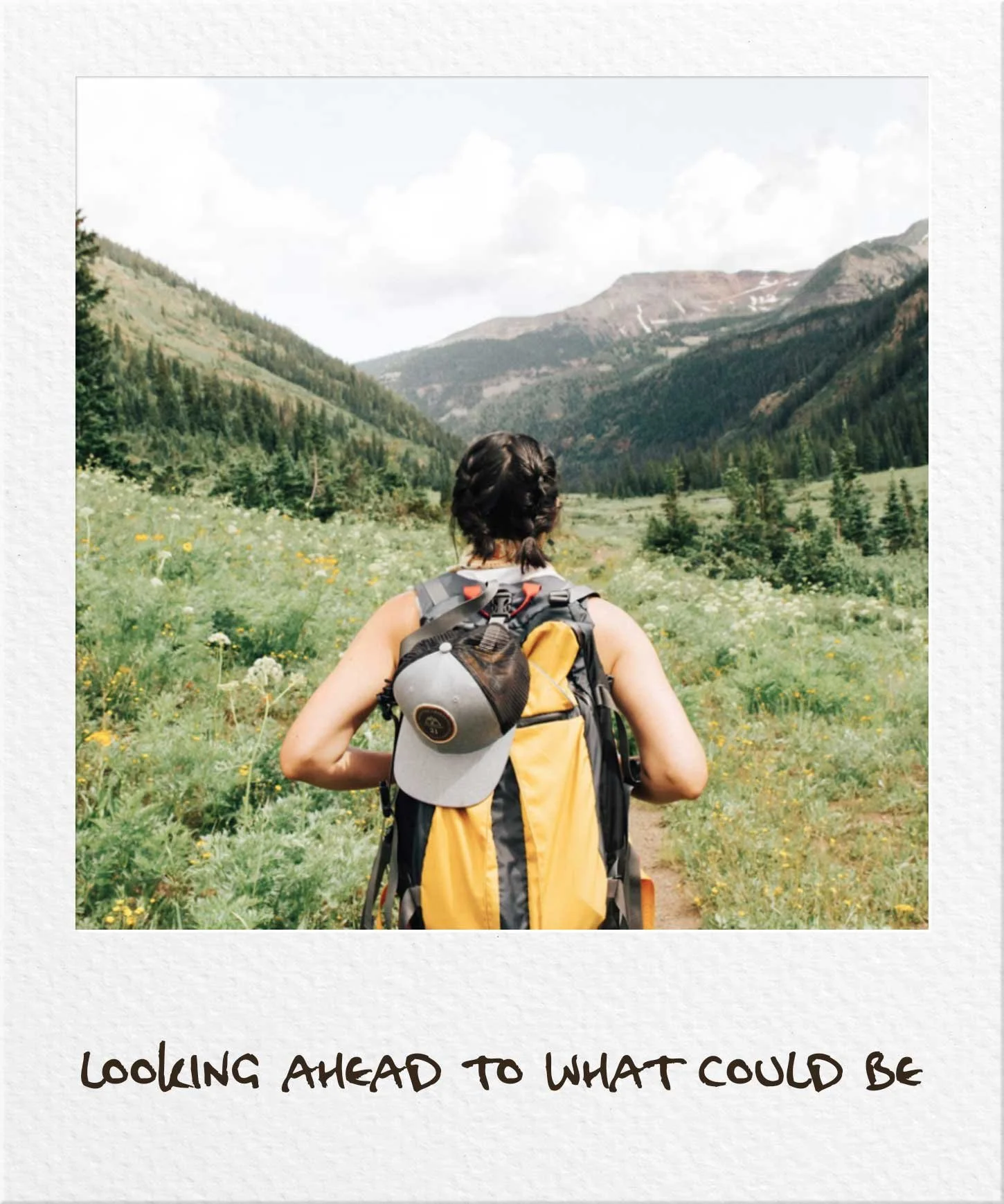 Girl wearing yellow backpack looking across at a valley of hills in a polaroid "looking ahead to what could be"
