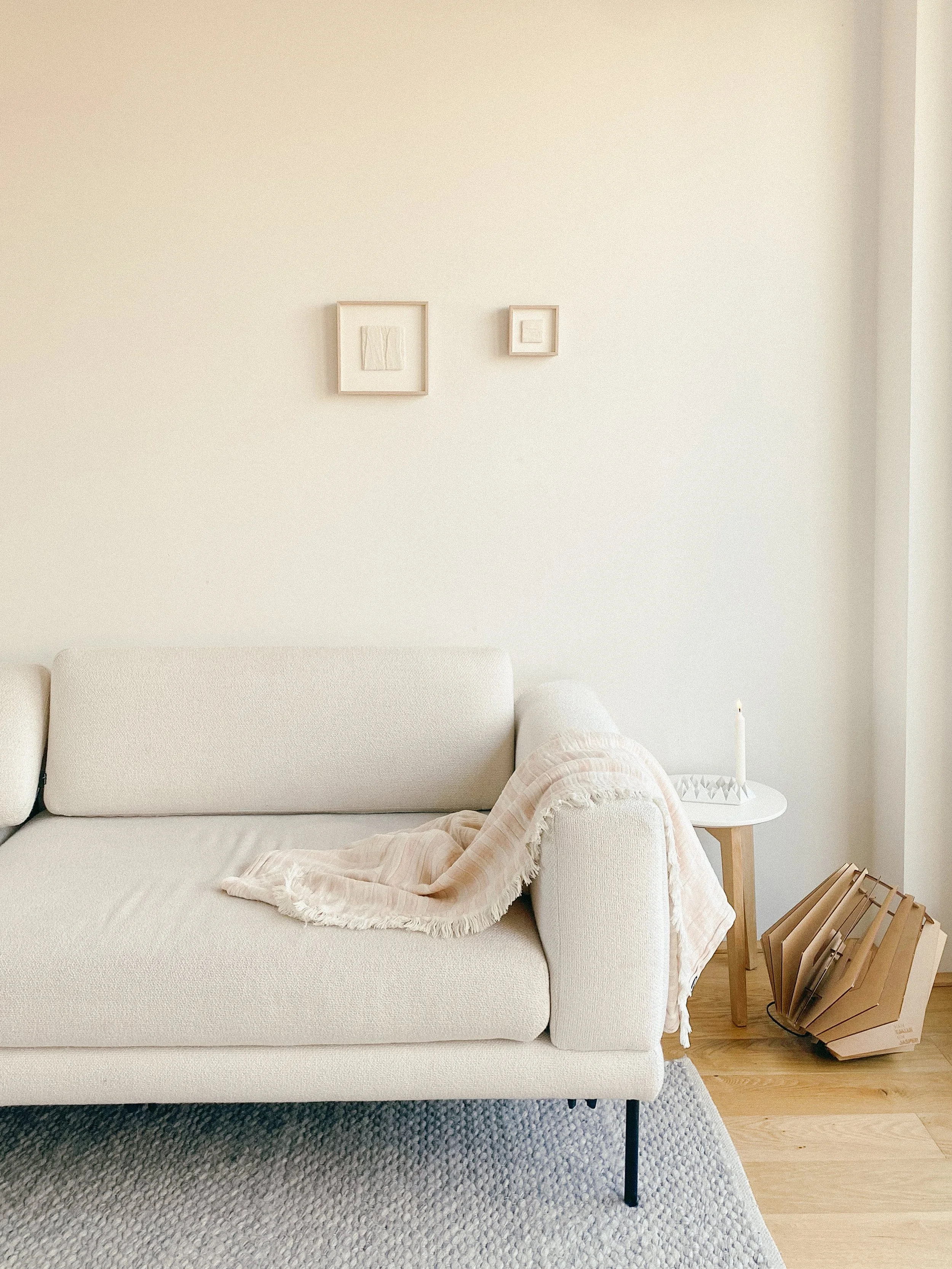 Two textile wall art pieces are hanging together  on the wall above a Bolia couch.