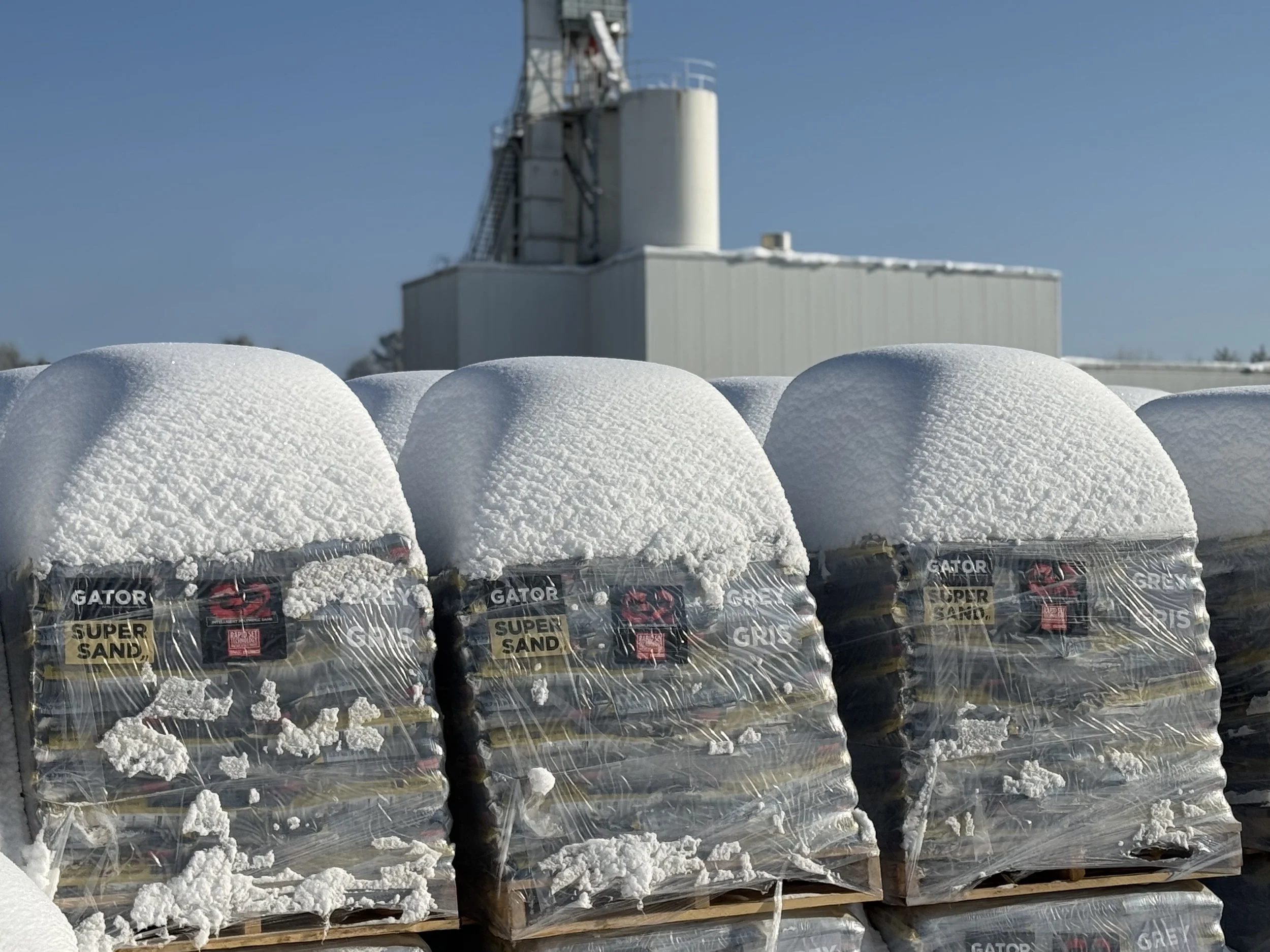 Pallets of polymeric sand stored in the snow