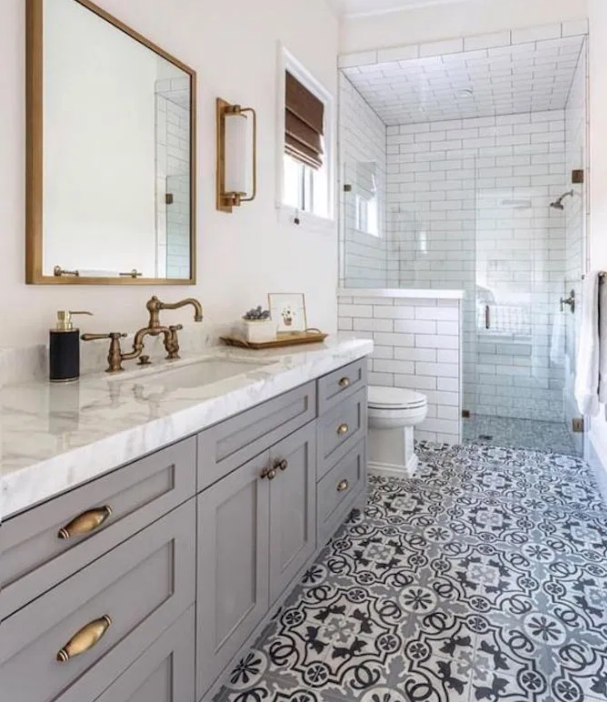 This beautiful complete bathroom renovation features moroccan style tile flooring and dark gold fixtures and accents. The paint color of the sink vanity flows perfectly into the intricate floor pattern, and the white marble countertops add a clean an
