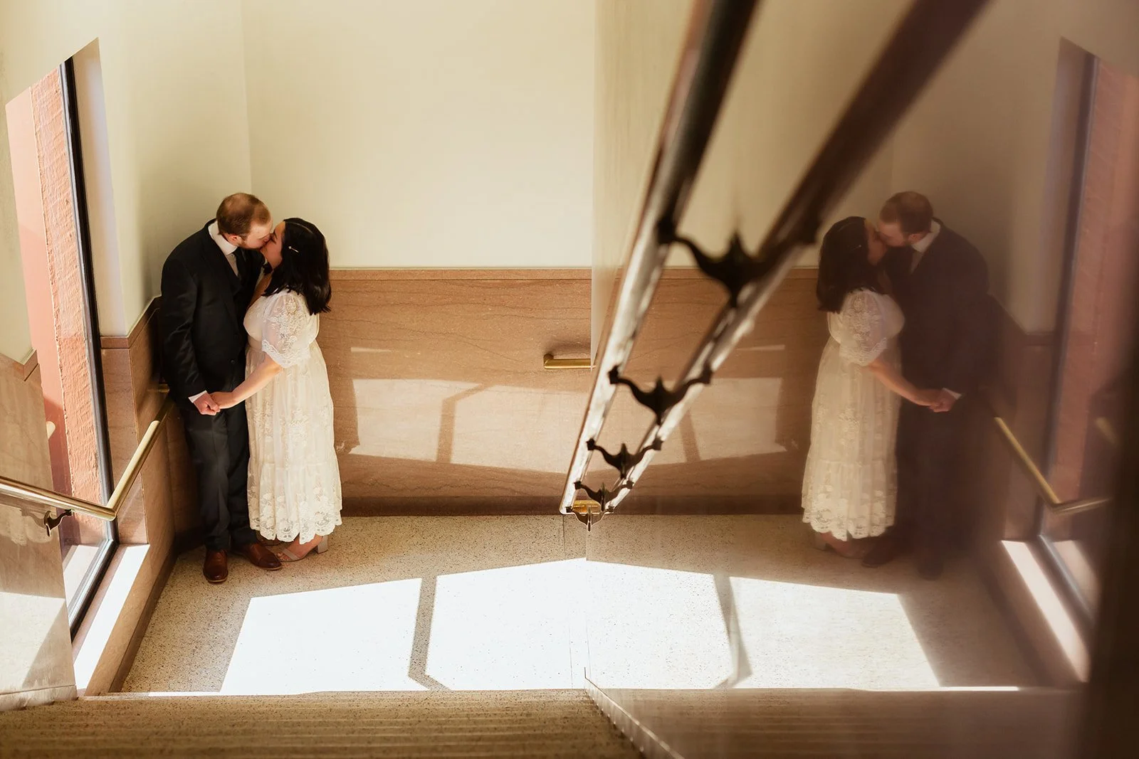 a couple embracing stands at the bottom of a set of stairs after their courthouse wedding.