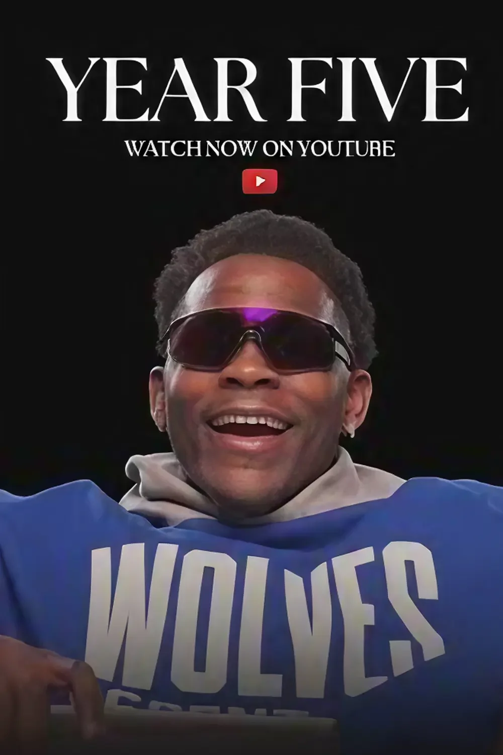 Promotional graphic featuring a smiling man wearing sunglasses and a blue sports jersey with the word "WOLVES" displayed. Text at the top reads "YEAR FIVE" with a subtitle "WATCH NOW ON YOUTUBE" and a red YouTube logo.