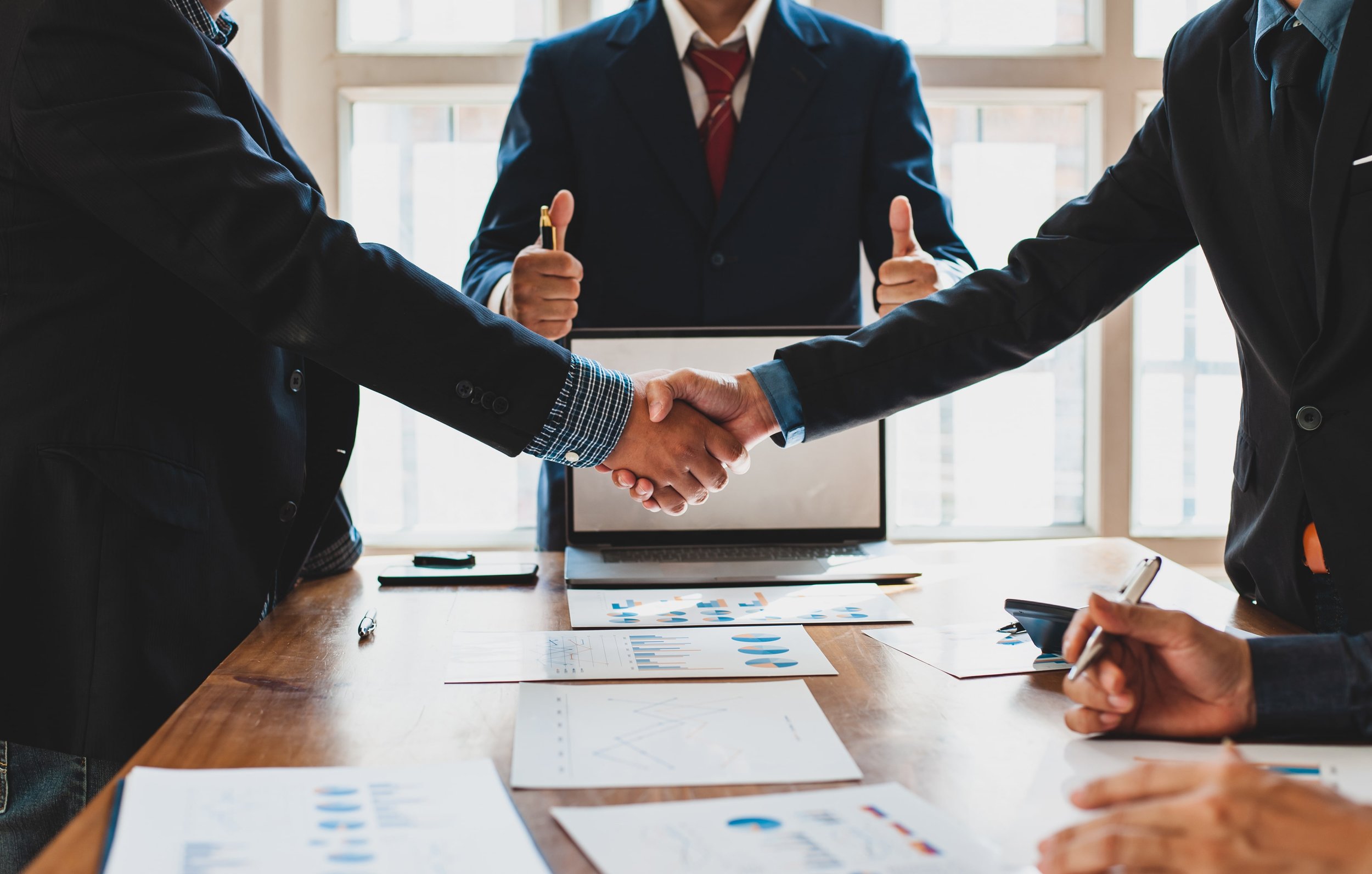 Collaborative Lawyers shaking hands in agreement over conference table