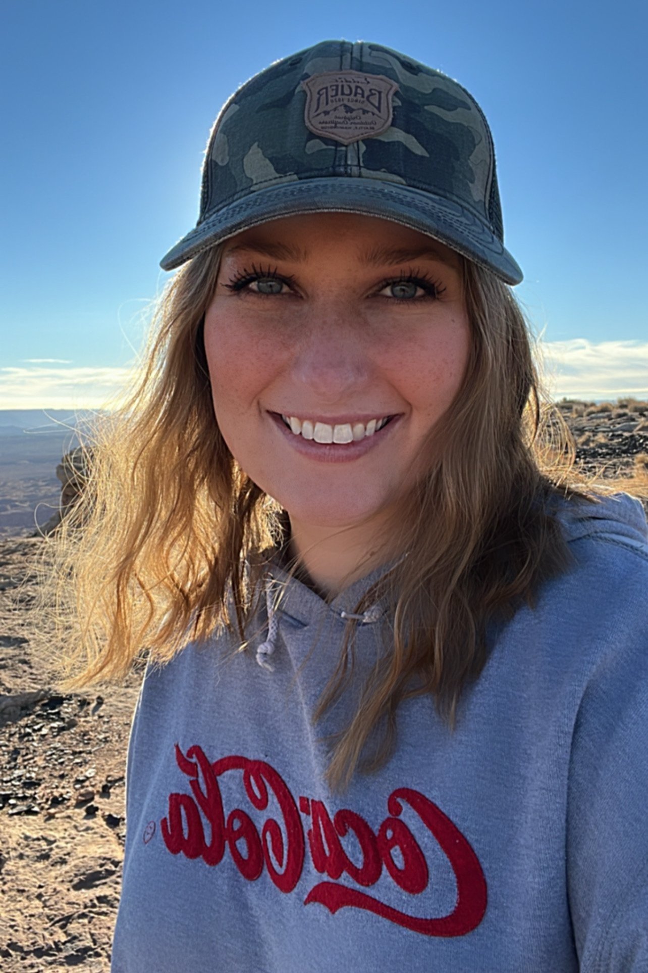 Future mother happy to be exploring on top of Tower Butte thanks to an awesome tour from Papillon Tours. Wearing a camouflaged hat and a Coca-Cola sweatshirt