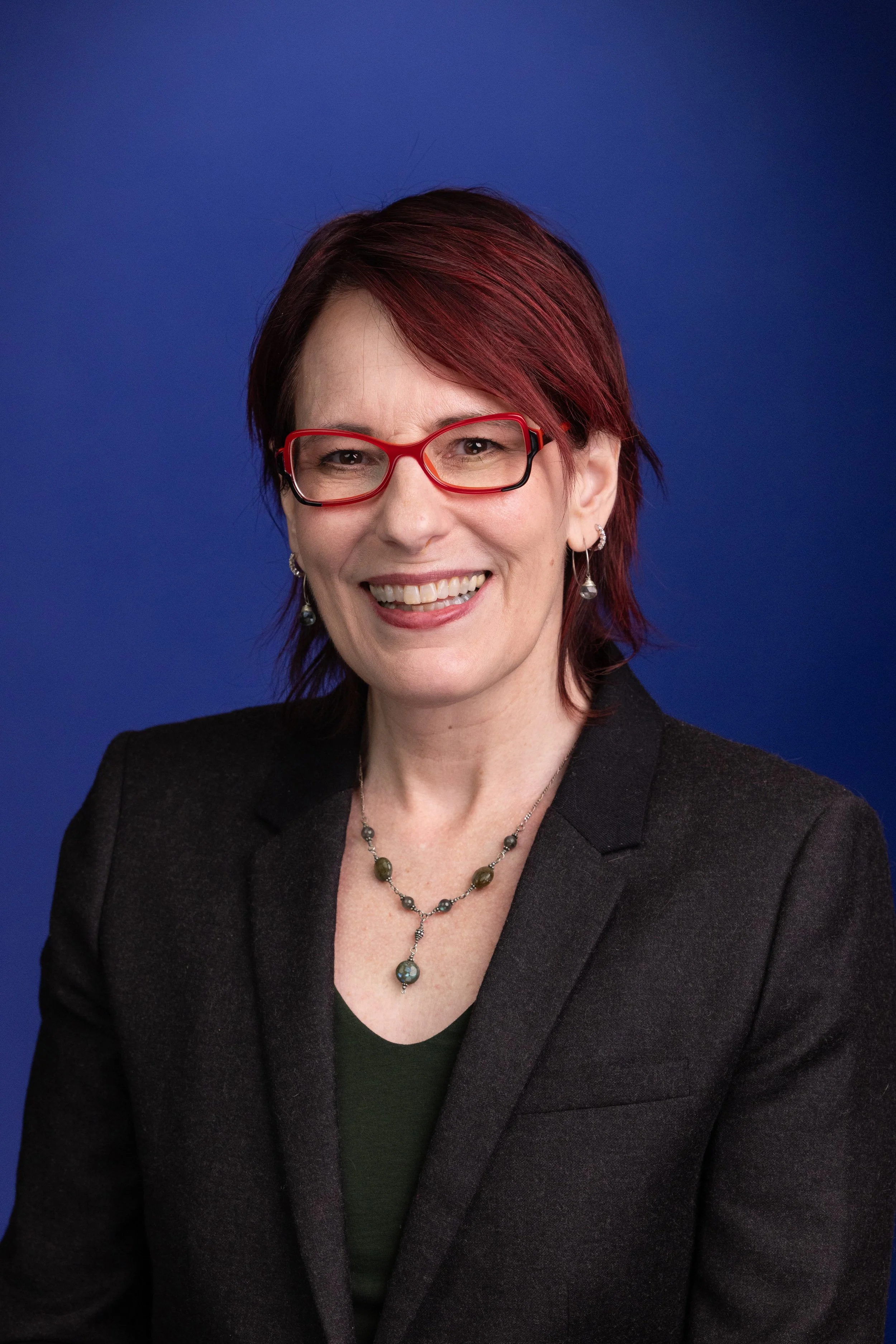 official KU photo of Barnette, a white woman with short auburn hair and red funky glasses