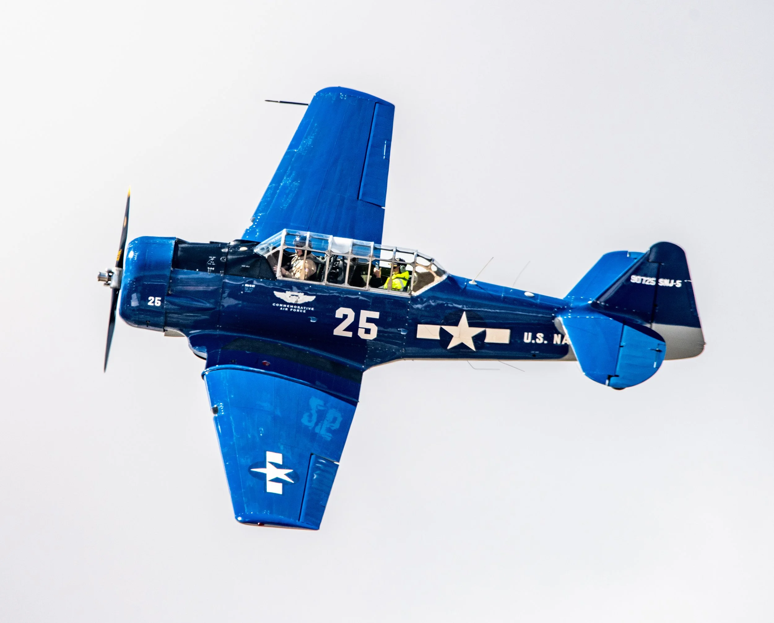 A blue vintage aircraft flying in the sky with US Air Force markings.
