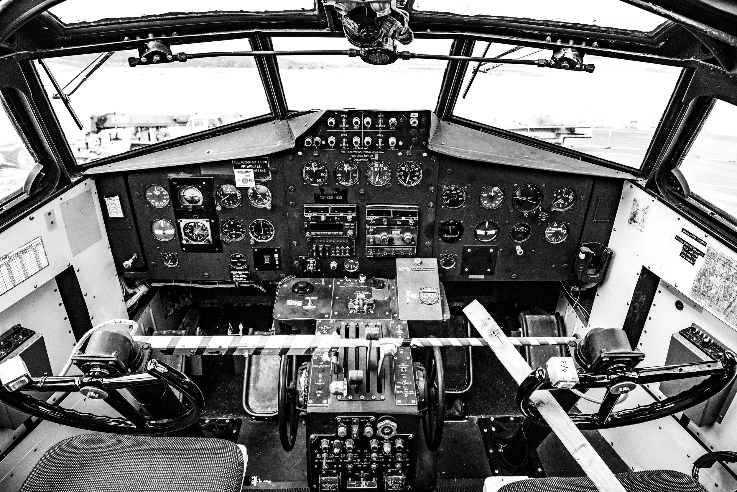 Black and white photo of an airplane cockpit with various gauges, controls, and steering mechanisms.