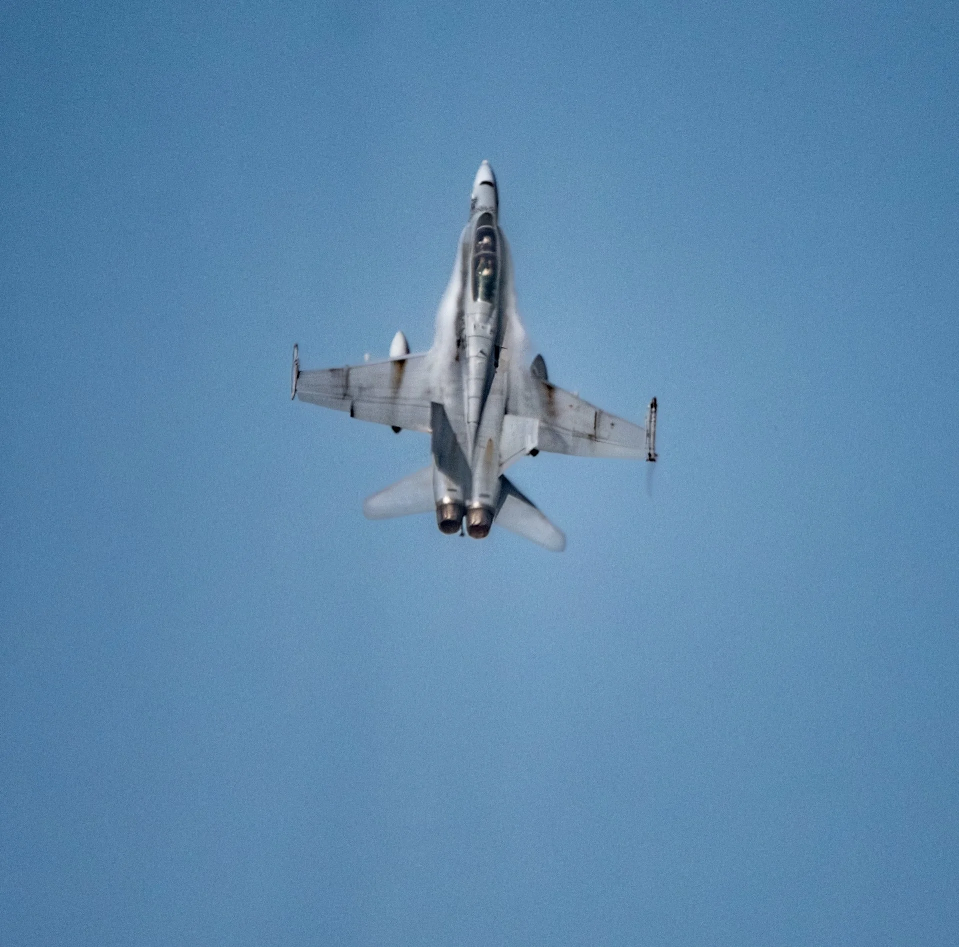 A fighter jet flying high in the sky, viewed from below.