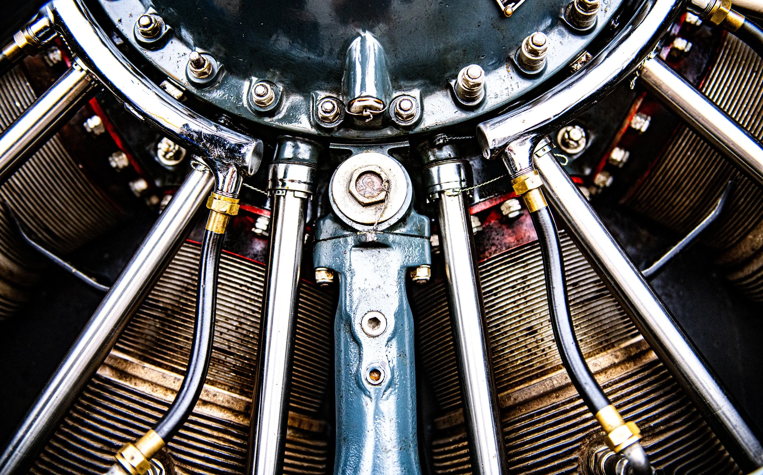 Close-up view of a vintage aircraft engine with metal pipes, bolts, and cylinders.