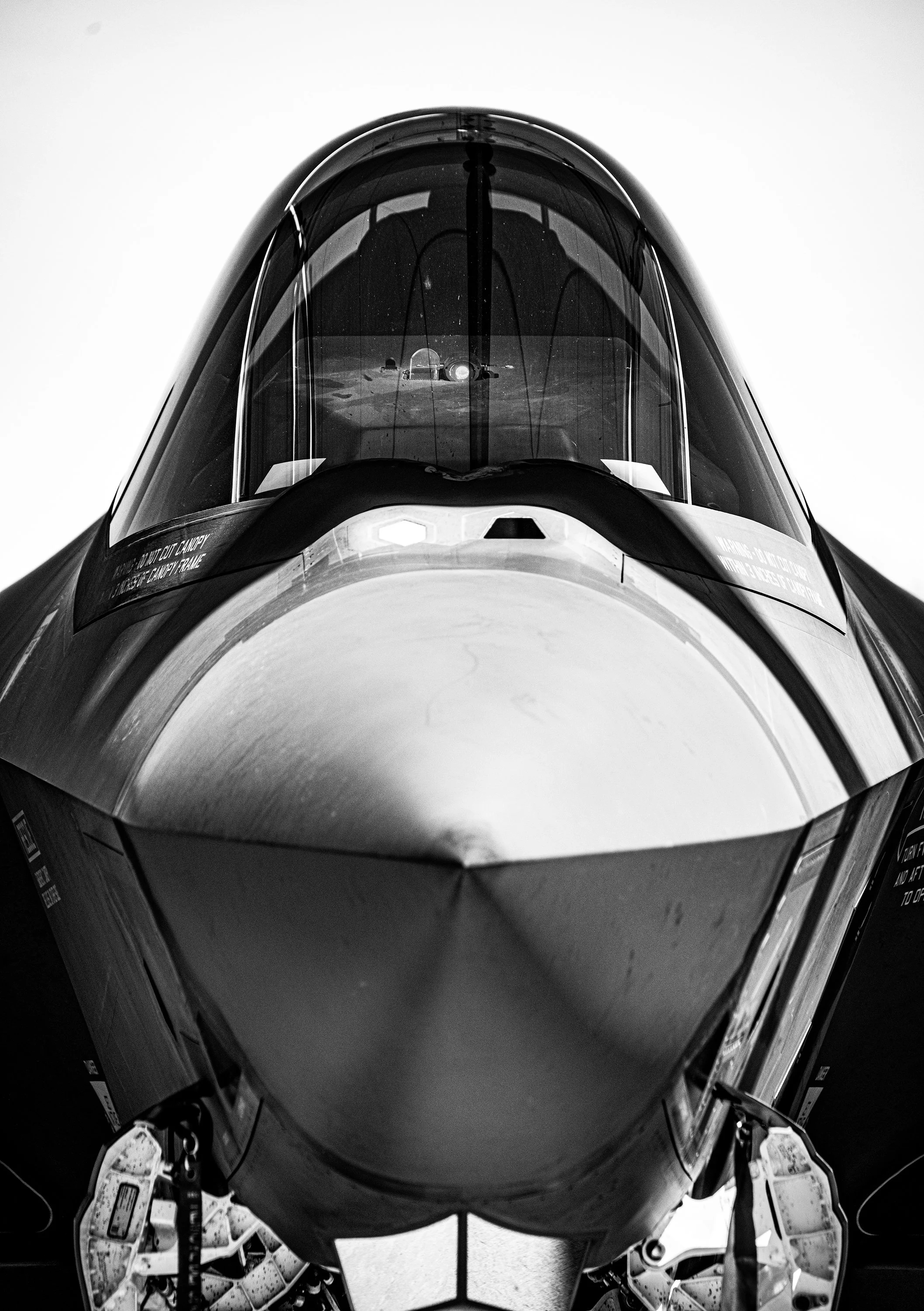 Front view of a fighter jet aircraft, black and white photo showing the nose and cockpit of the jet.
