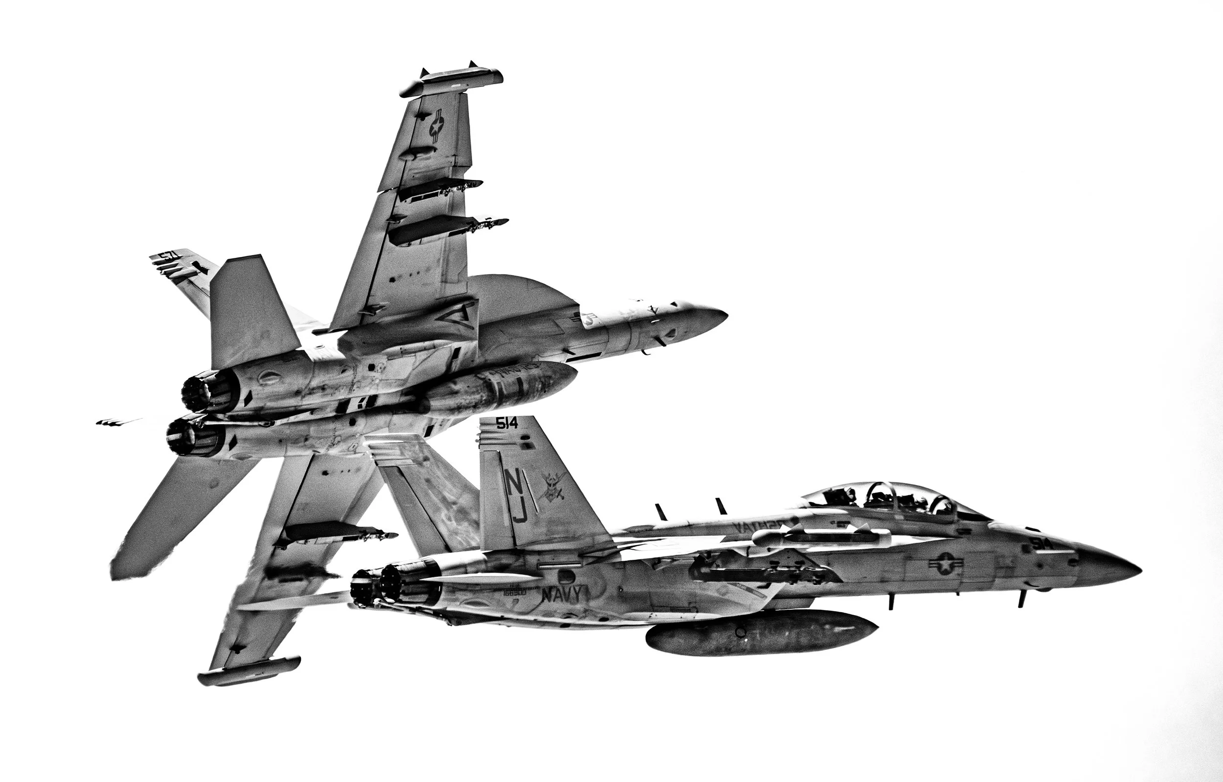 Two fighter jets flying in formation in a black and white aerial photograph, one above the other against a plain sky.