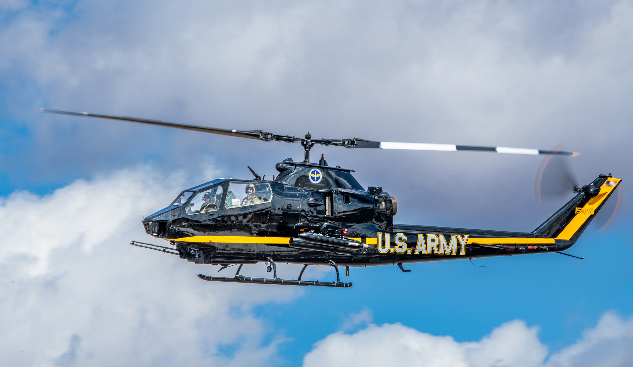 U.S. Army black helicopter flying in a cloudy sky