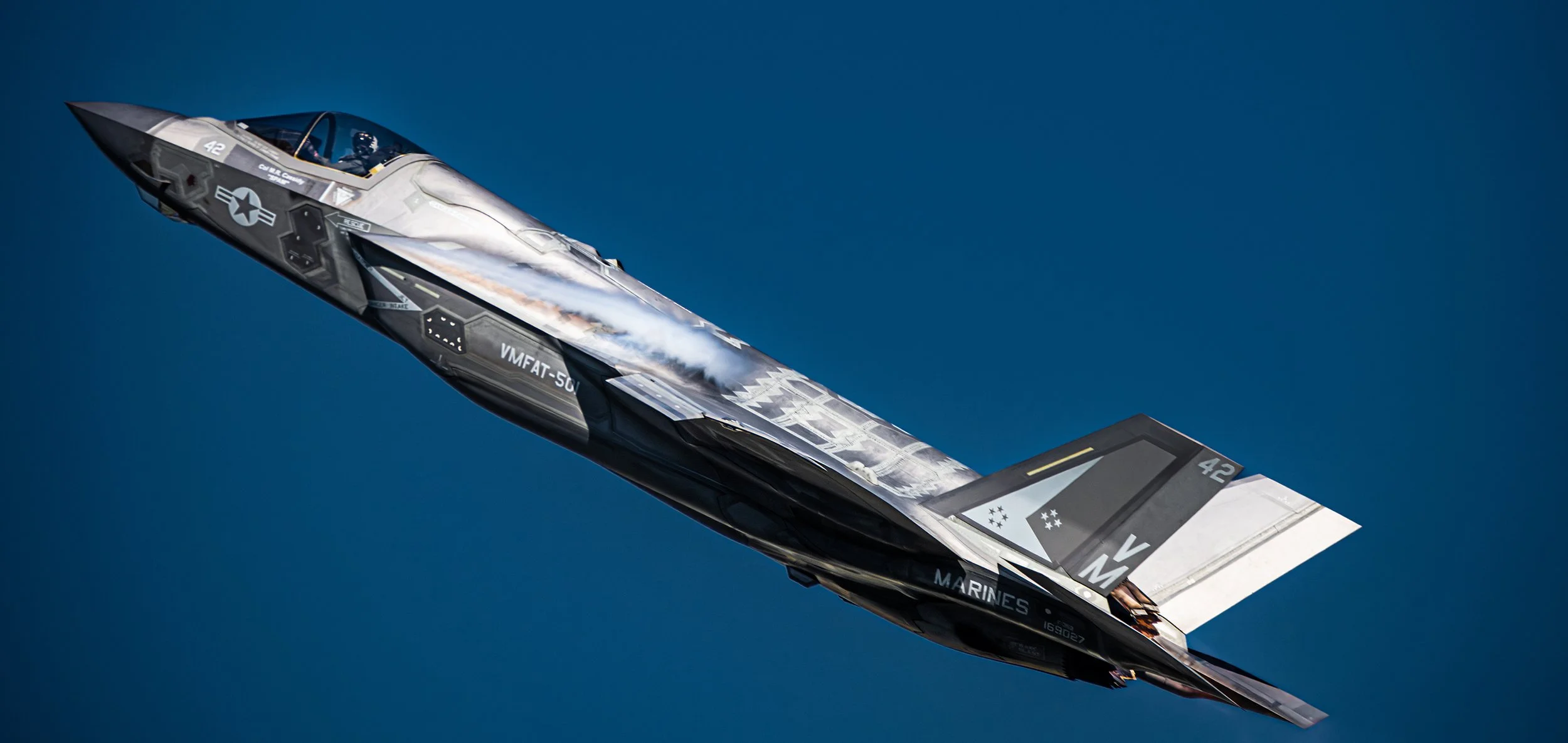 F-35 fighter jet flying in clear blue sky.