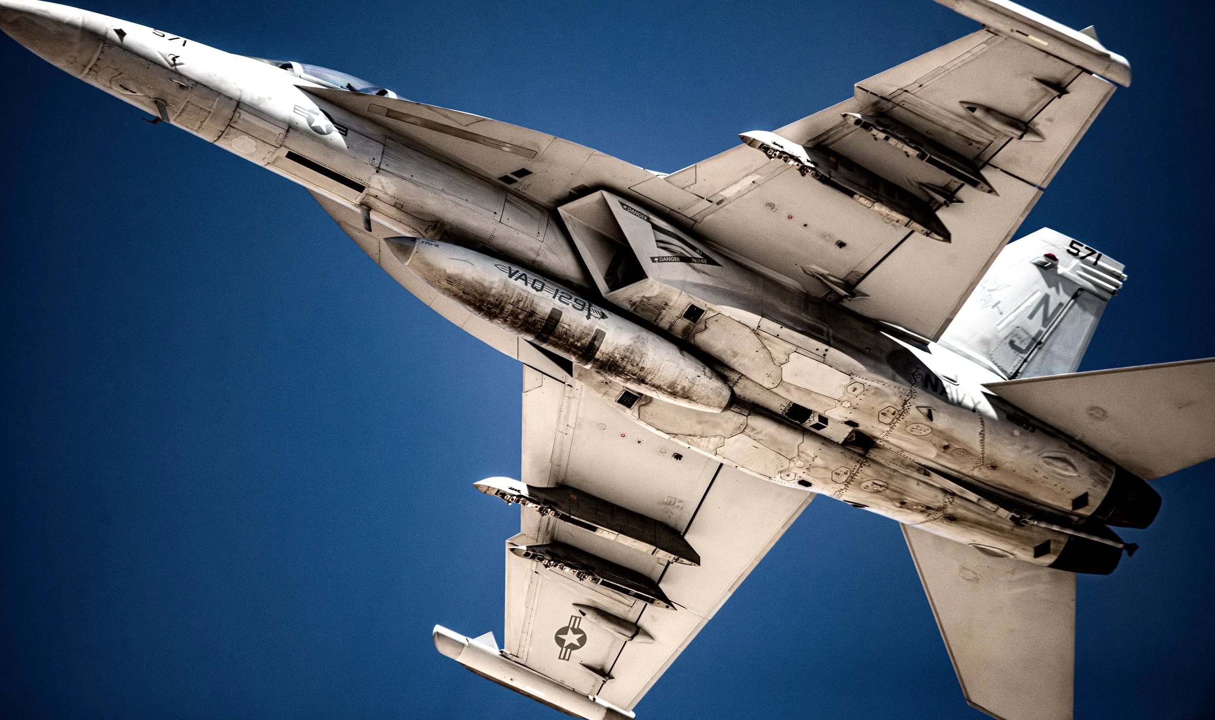 A fighter jet flying in clear blue sky, shown from below.