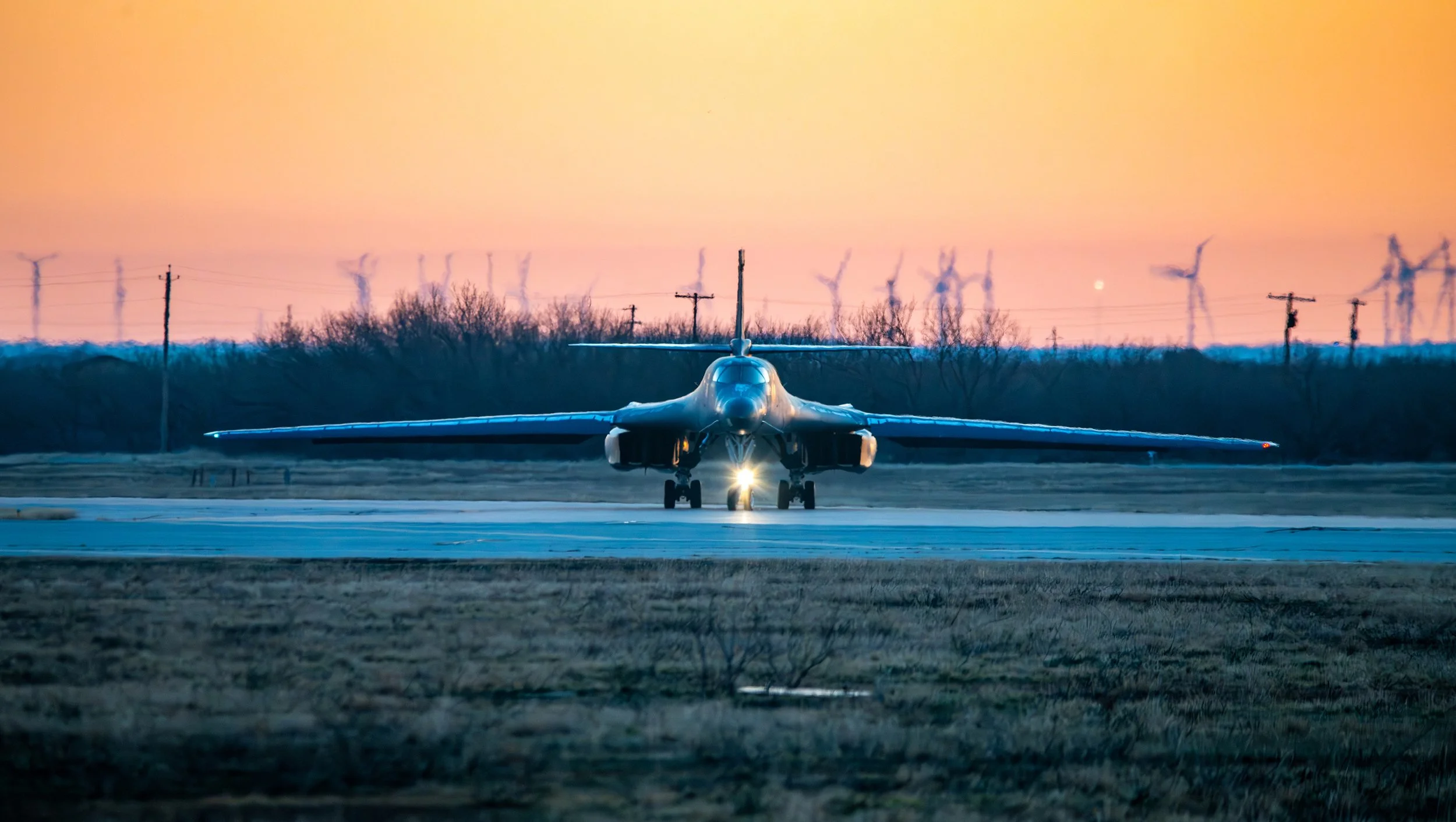 Military fighter jet aircraft on runway at sunset