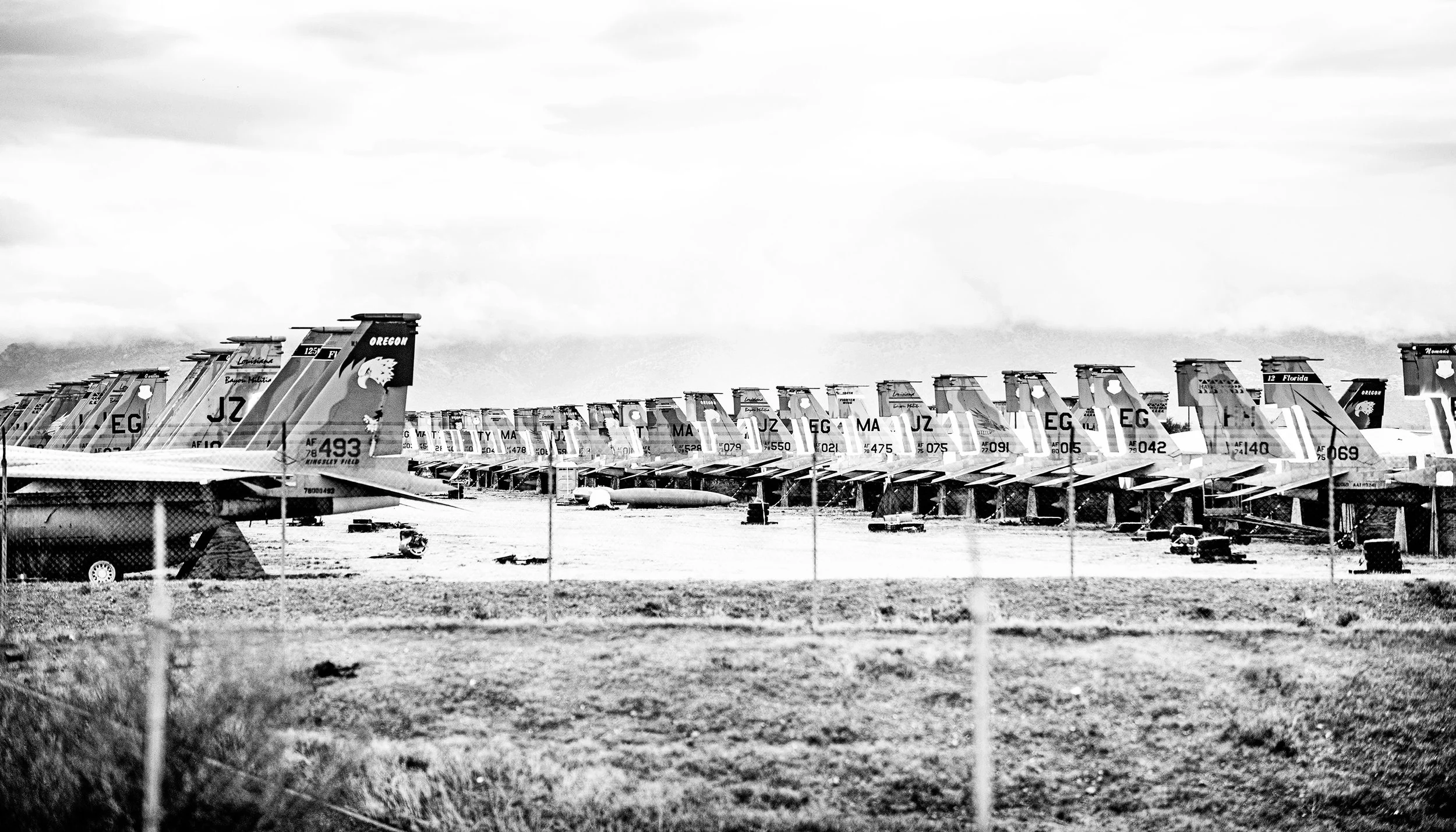Row of aircrafts parked at an airfield, viewed in black and white.