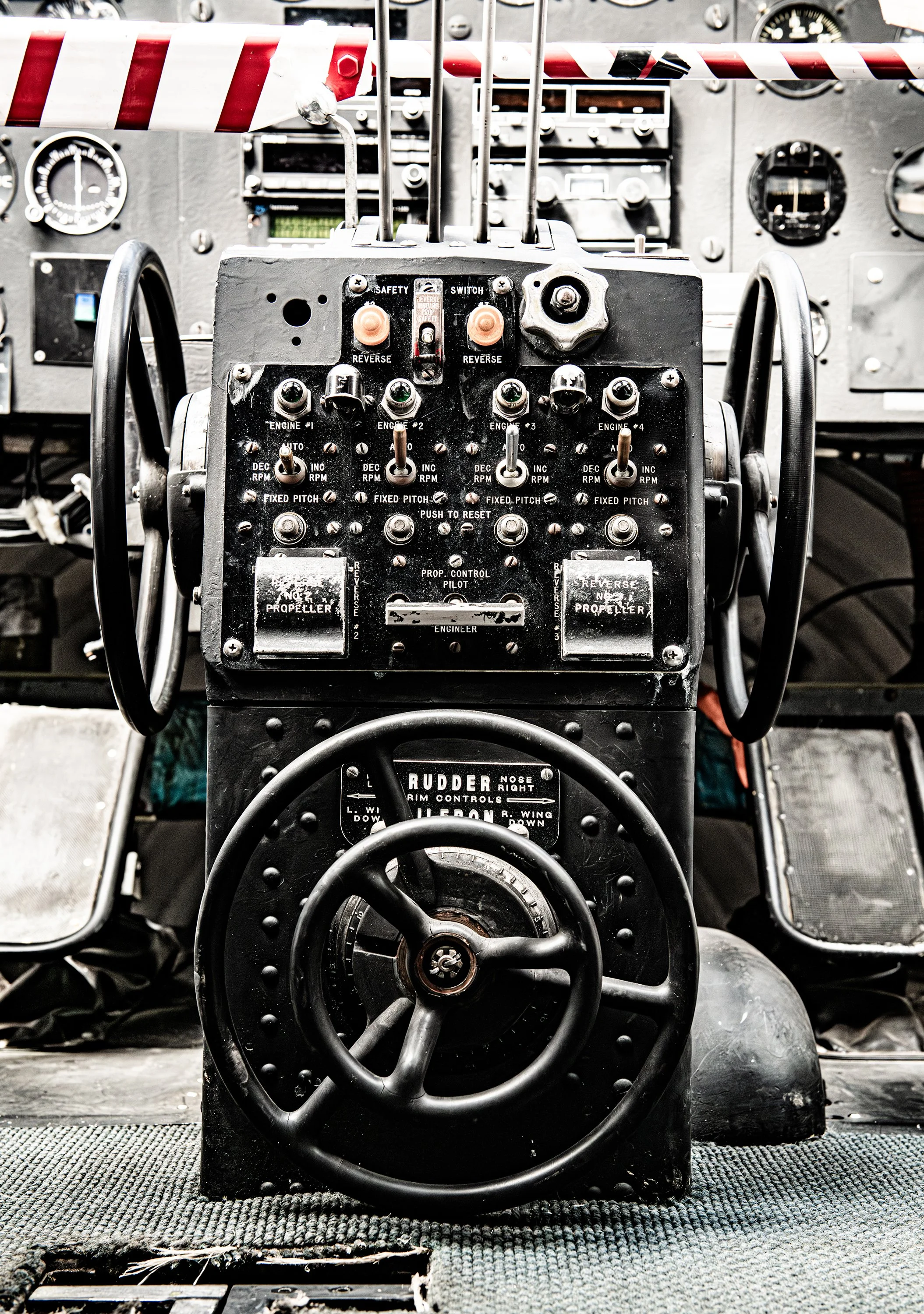 Close-up of vintage aircraft cockpit controls with various switches, dials, and a steering wheel.