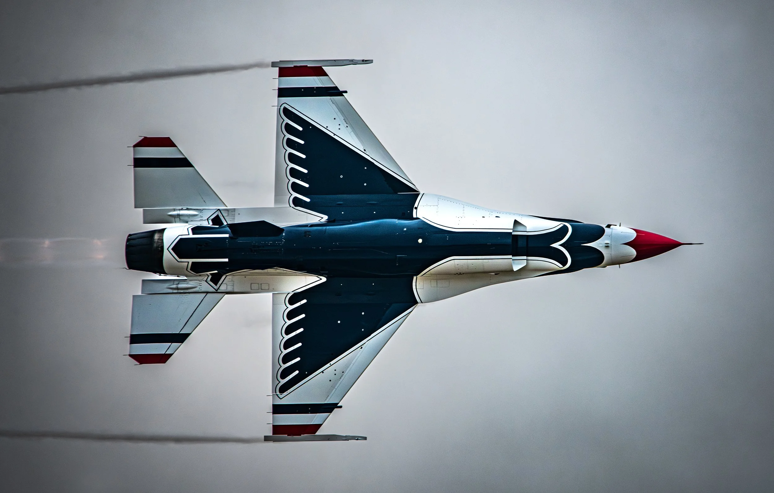 An aircraft flying upside down, displaying red, white, and blue designs on the wings and fuselage.