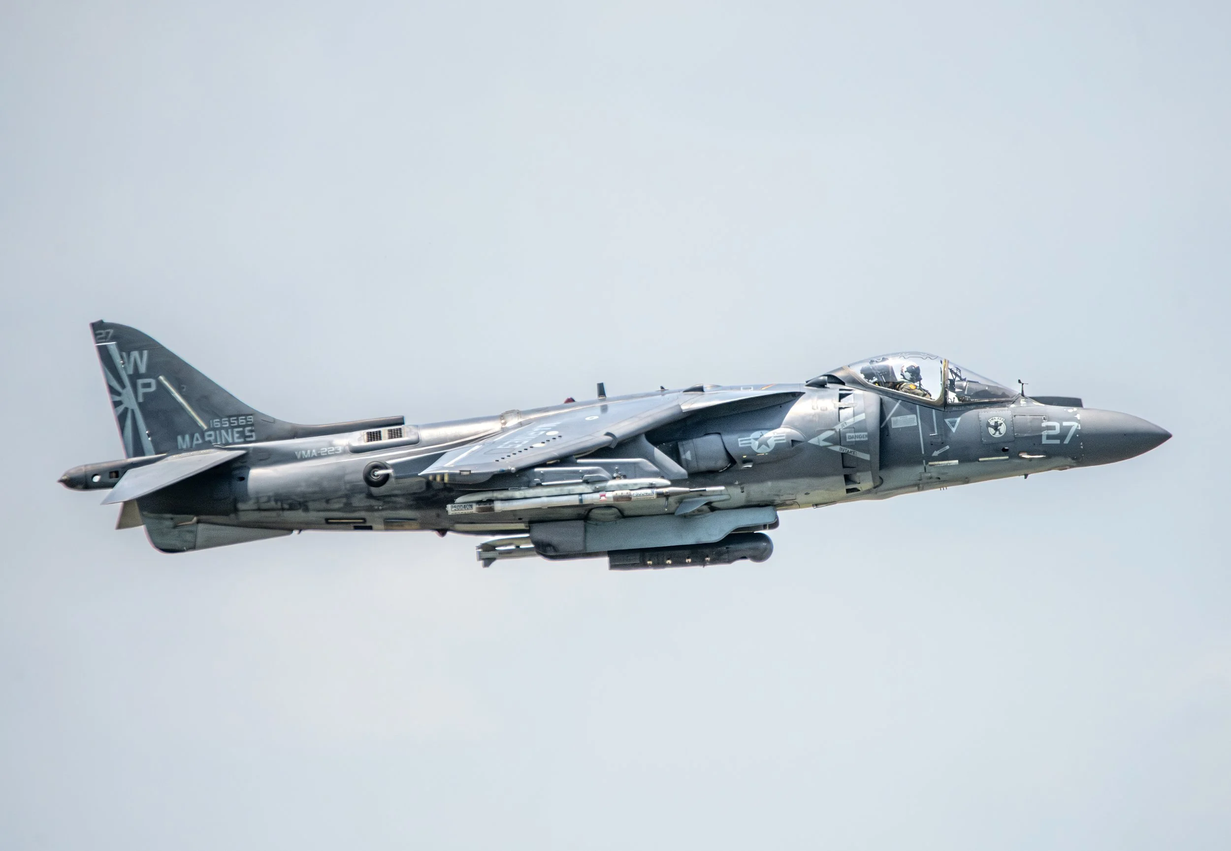 A military fighter jet flying against a cloudy sky.