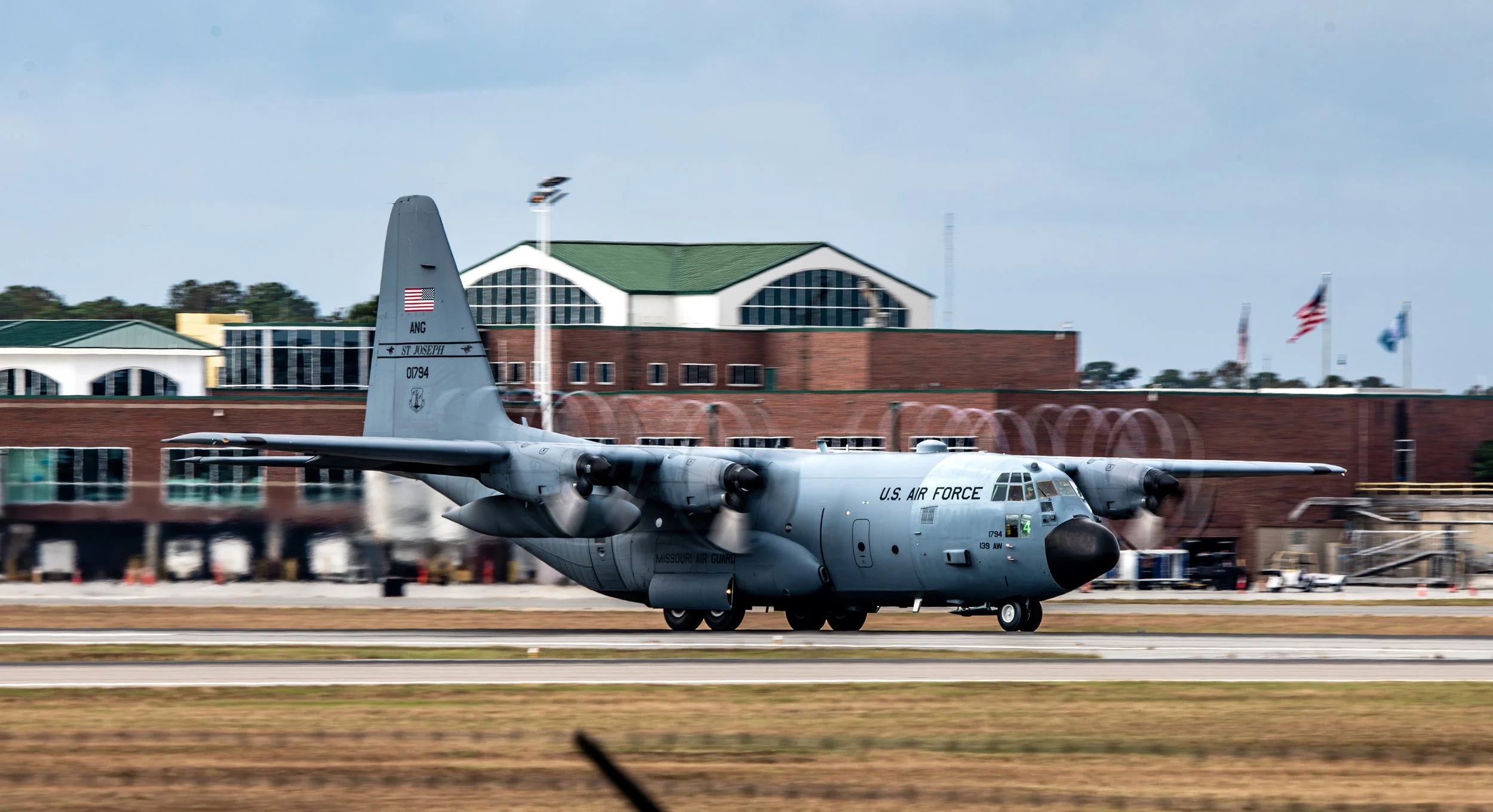 A U.S. Air Force C-130 Hercules cargo aircraft on the runway at an airport.