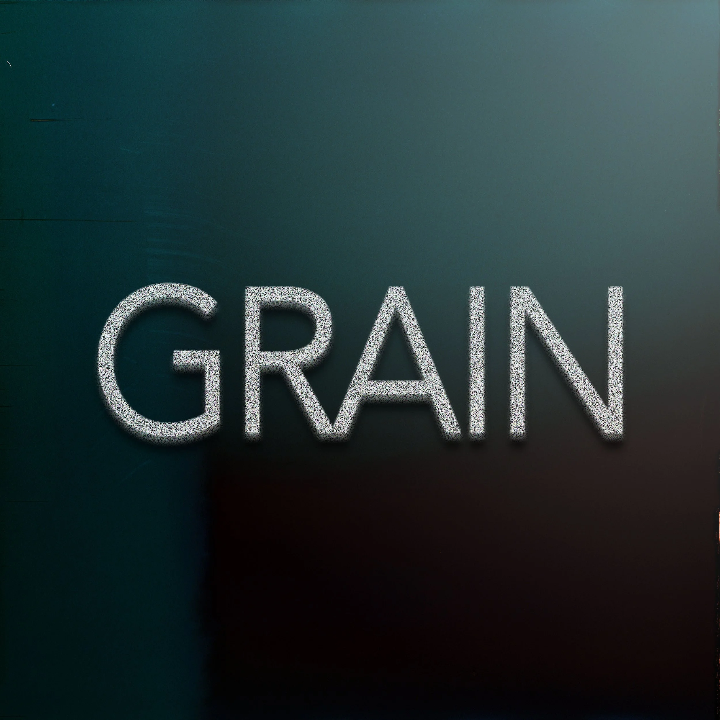 Close-up of the word 'GRAIN' in white, textured font on a dark, blurred background.
