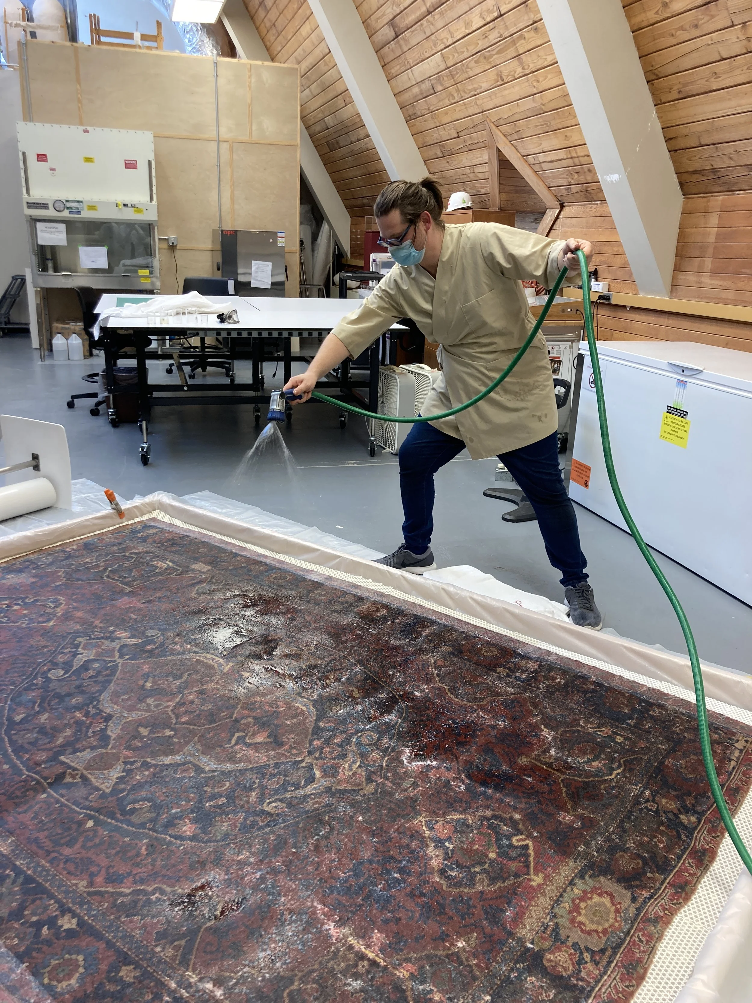 Riley Cruttenden rinsing the rug with our DIY DI garden hose.