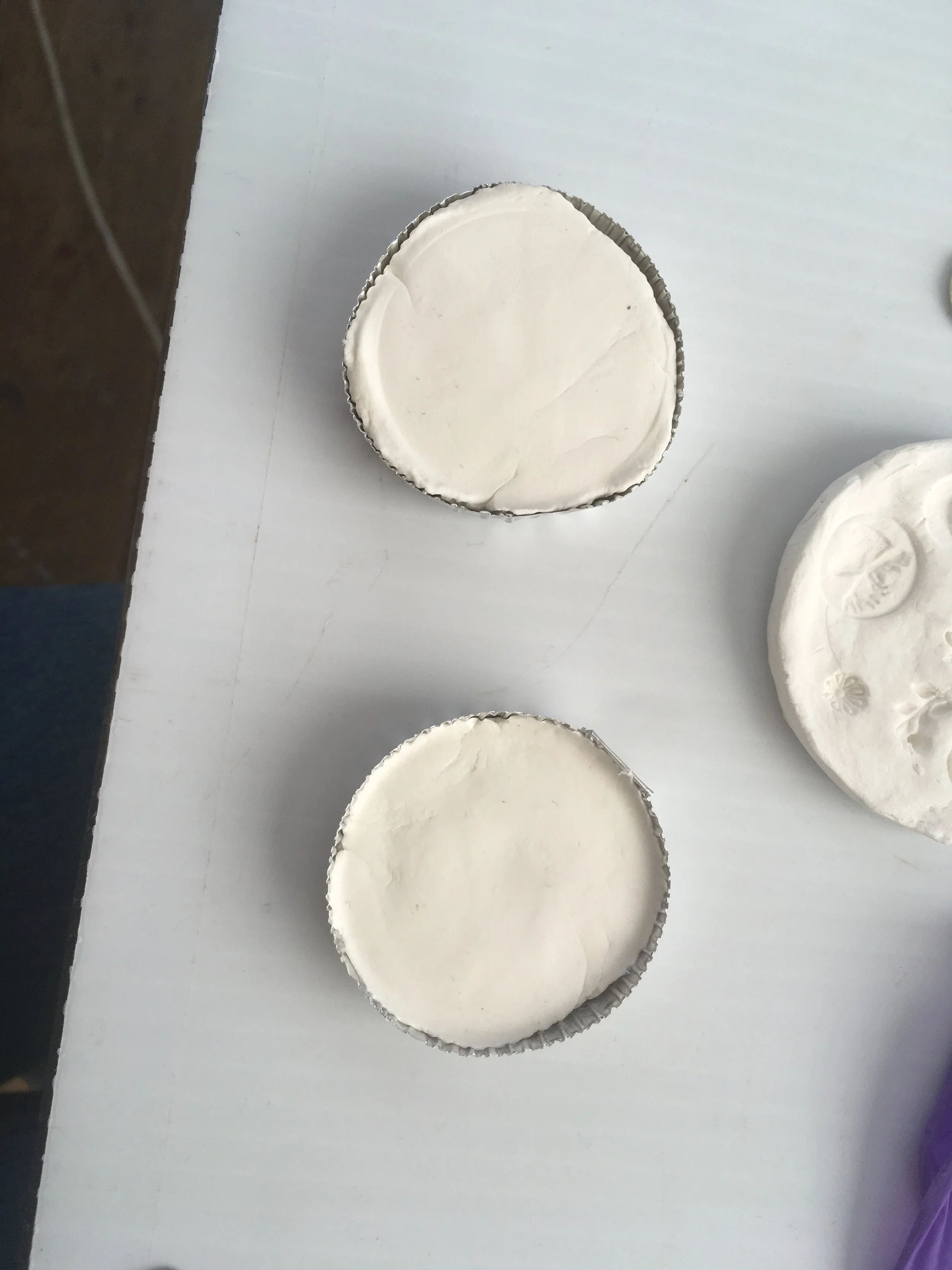 Flat disks of air dry clay were made in round tin containers.