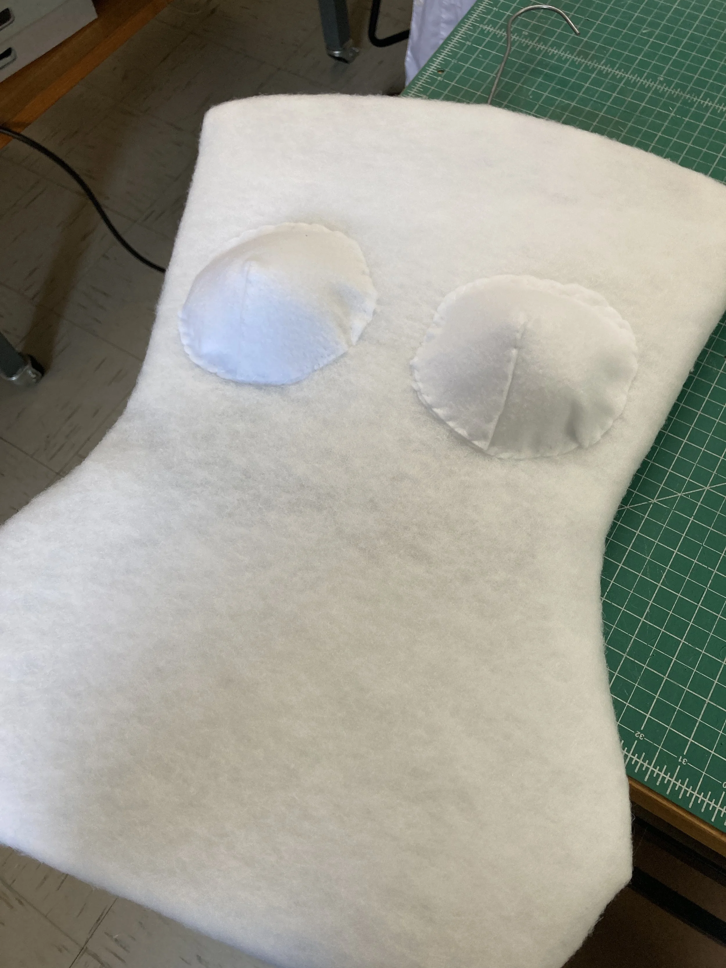 Cut out the blueboard- fit it. Add polybatting on the bust and hip on both sides with double sided tape. Lash a hanger to the blueboard. Add polybatting to the front and back and sew in place. Fit and mark bust points. Add padded felt bust pads.