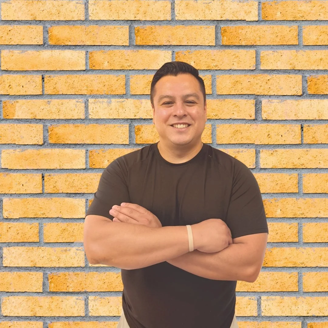 Young man, standing with his arms crossed in front a brick wall