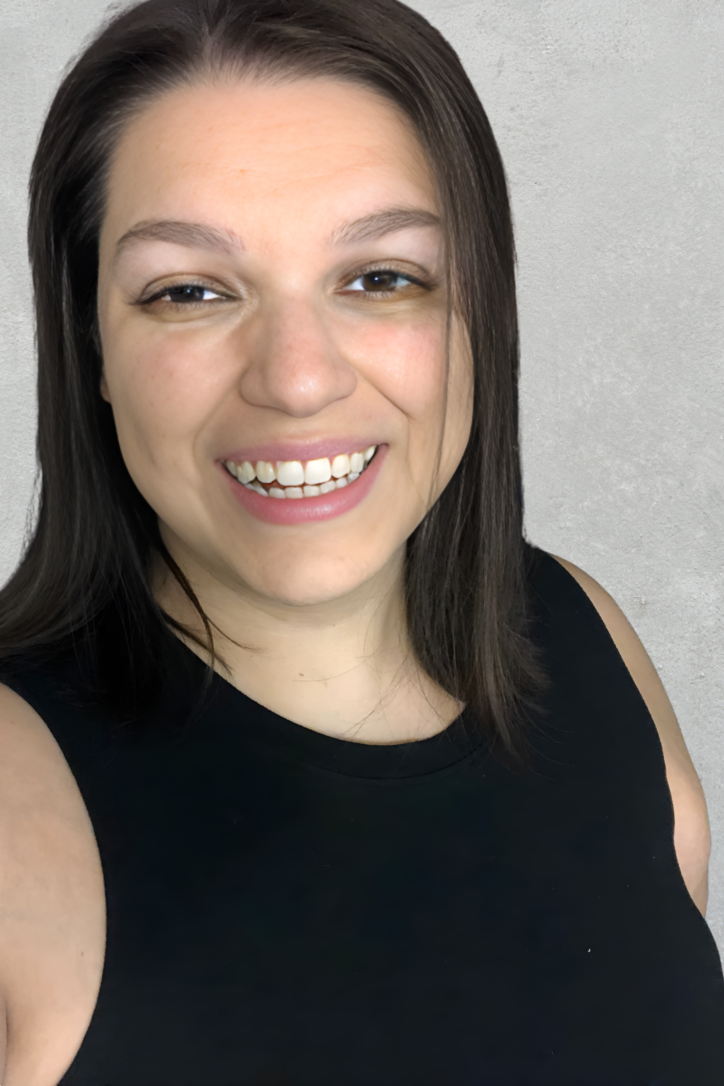 A woman smiling, wearing a black sleeveless top, with dark hair and a light gray background.