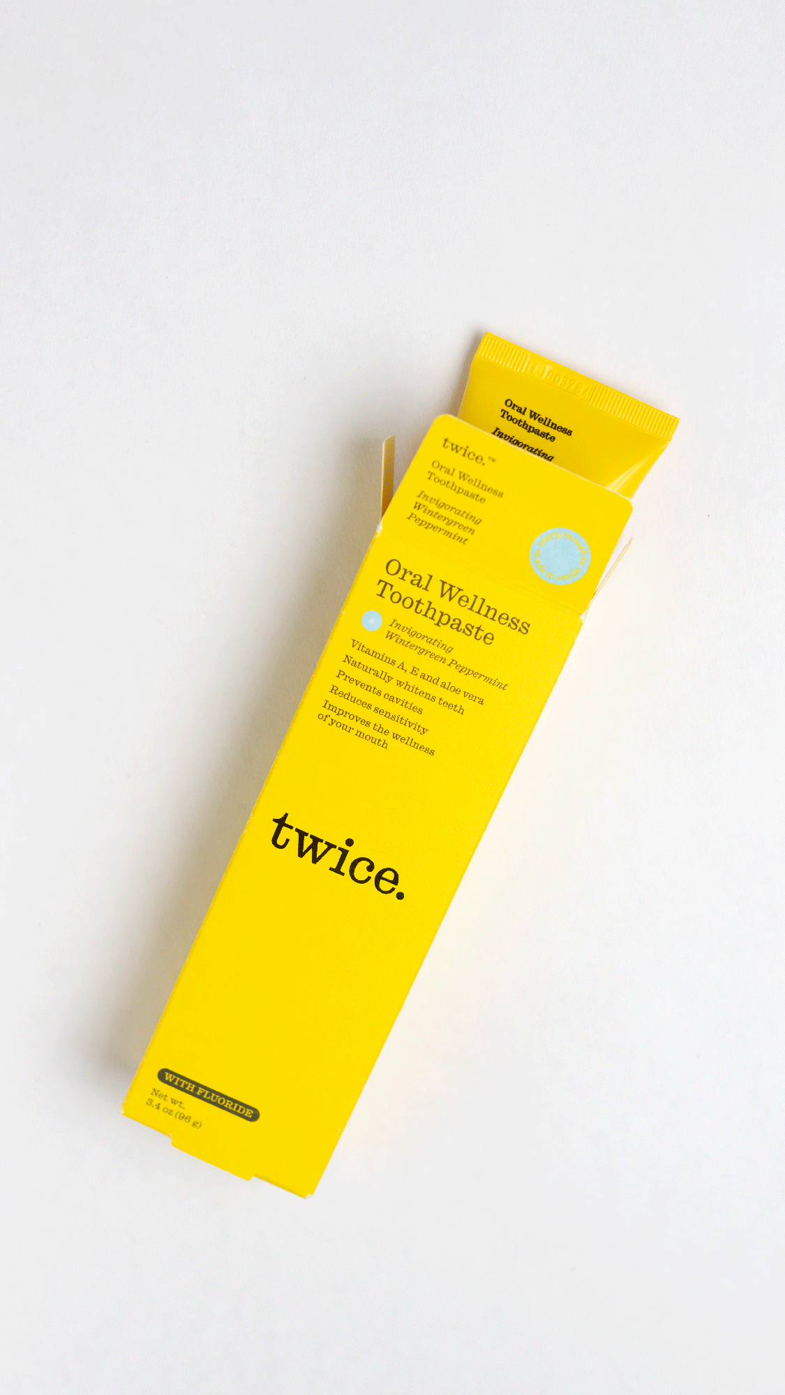 Yellow box of Twice Oral Wellness Toothpaste with the tube partially out.