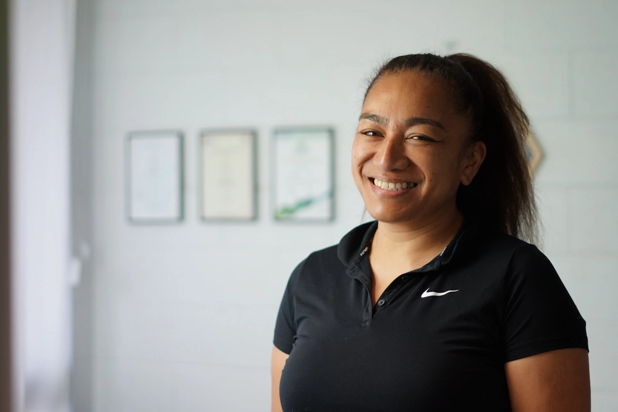 Melissa Latu, a former Australian Rugby player standing in front of her qualifications.