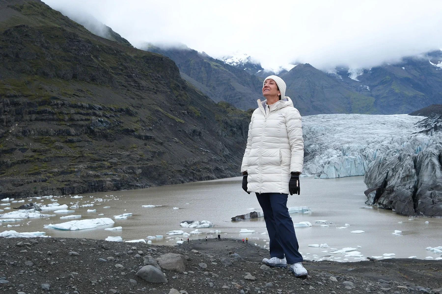 Traveler on a private accessible tour in Iceland standing at the edge of a glacier lagoon with icebergs