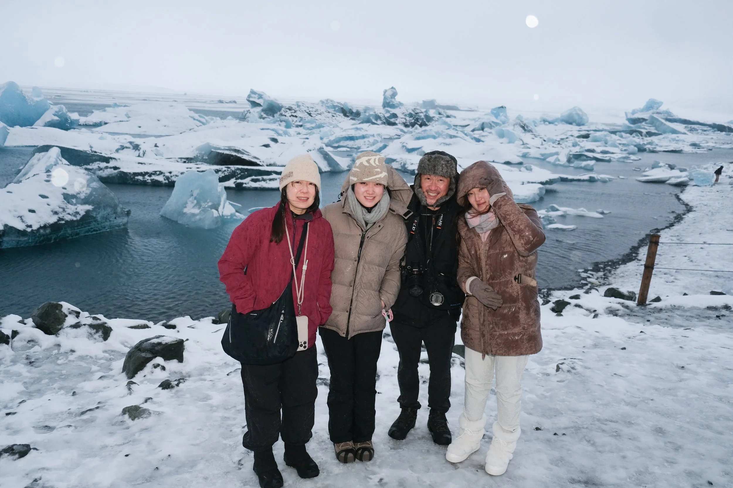 Four people standing in front of icy landscape with icebergs and snow, Glacier Lagoon & Ice Caves