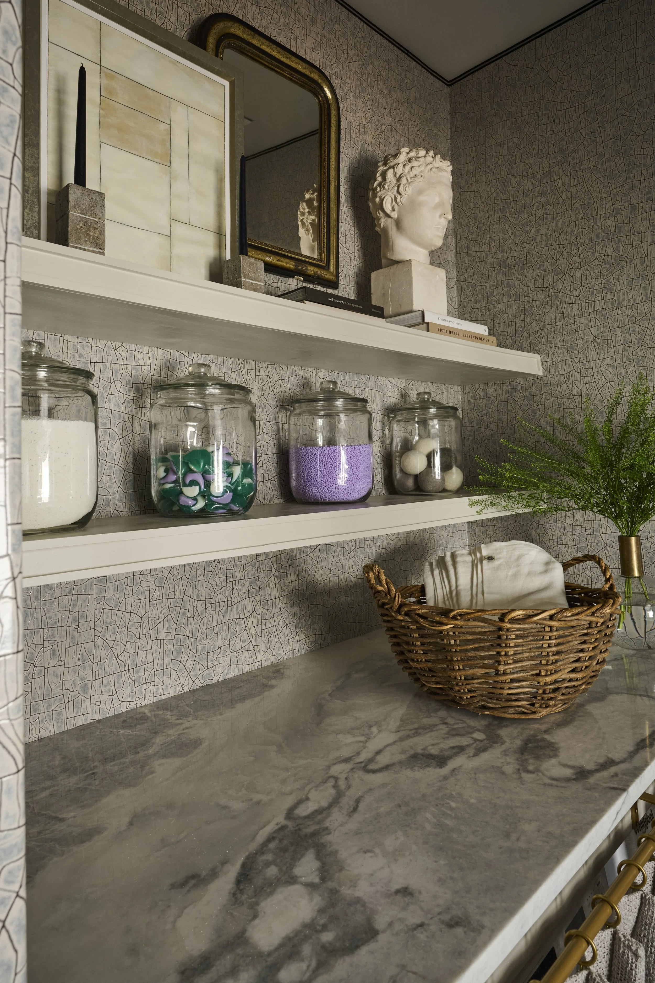 Serenbe Showhouse Laundry Shelves. Wallpaper from Arte Wallcoverings at Paul Plus with a Holly Hunt Tape Trim Border. layered with antiques and accessories. Organization storage for laundry needs.