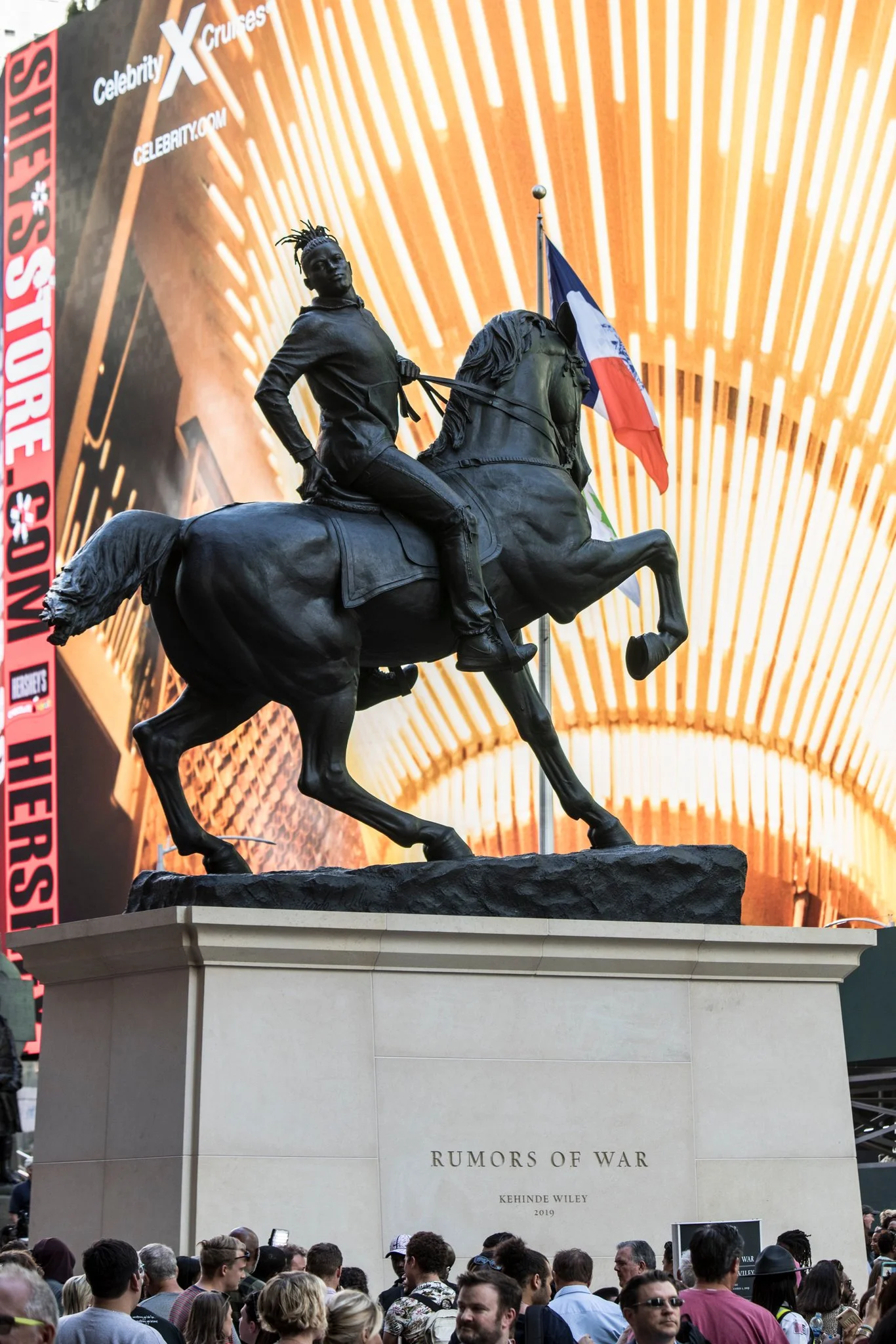 Kehinde Wiley's statue "Rumors of War" in Times Square depicts a young Black man with his locs tied back, springing up behind his head like a crown. He is wearing a hoodie and ripped jeans and a pair of Nike's. He rides a muscled horse mid-stride.