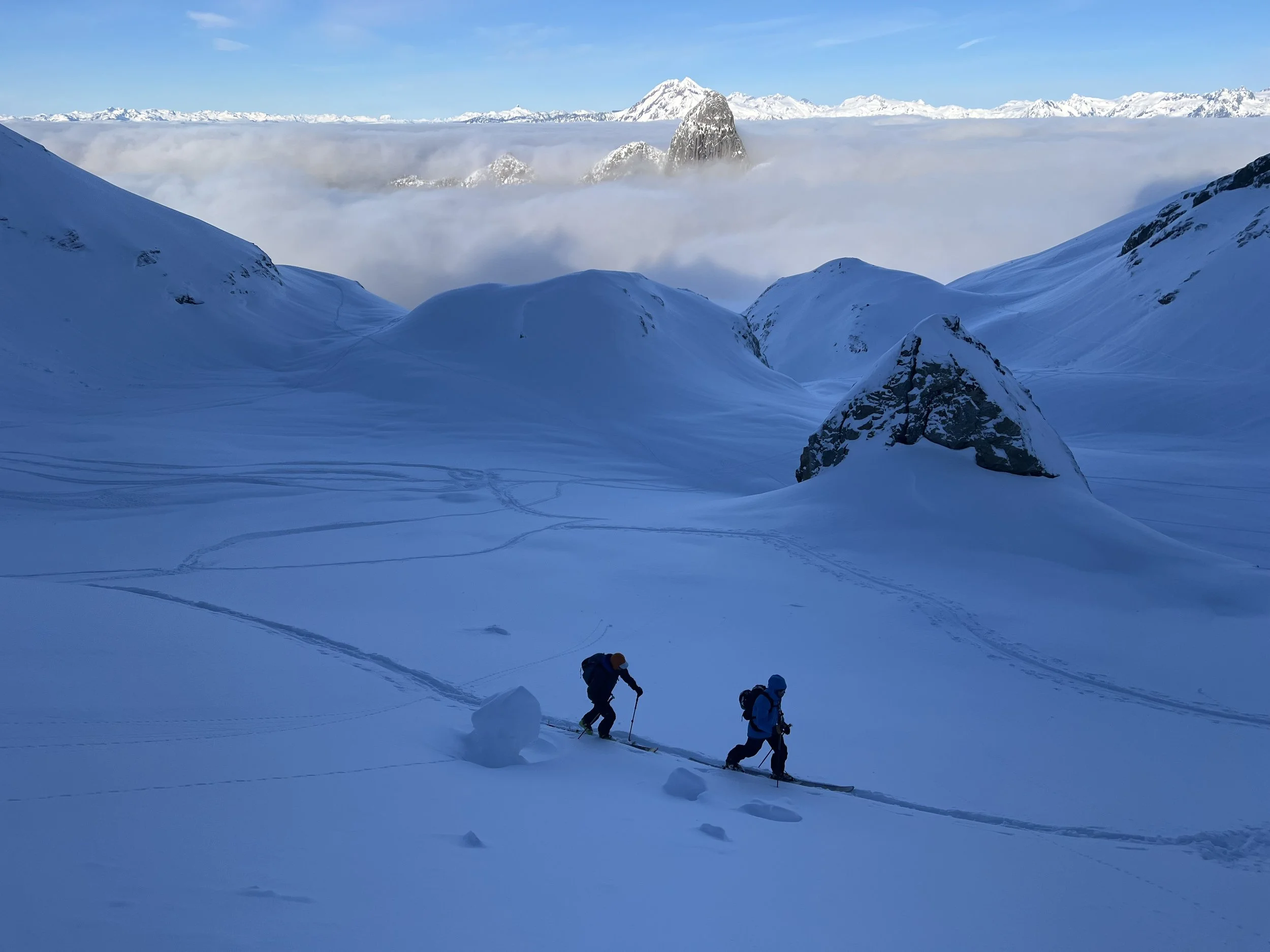 Ski touring up the Stadium Glacier with Mt. Habrich and Garibaldi protruding from a sea of clouds in the background.