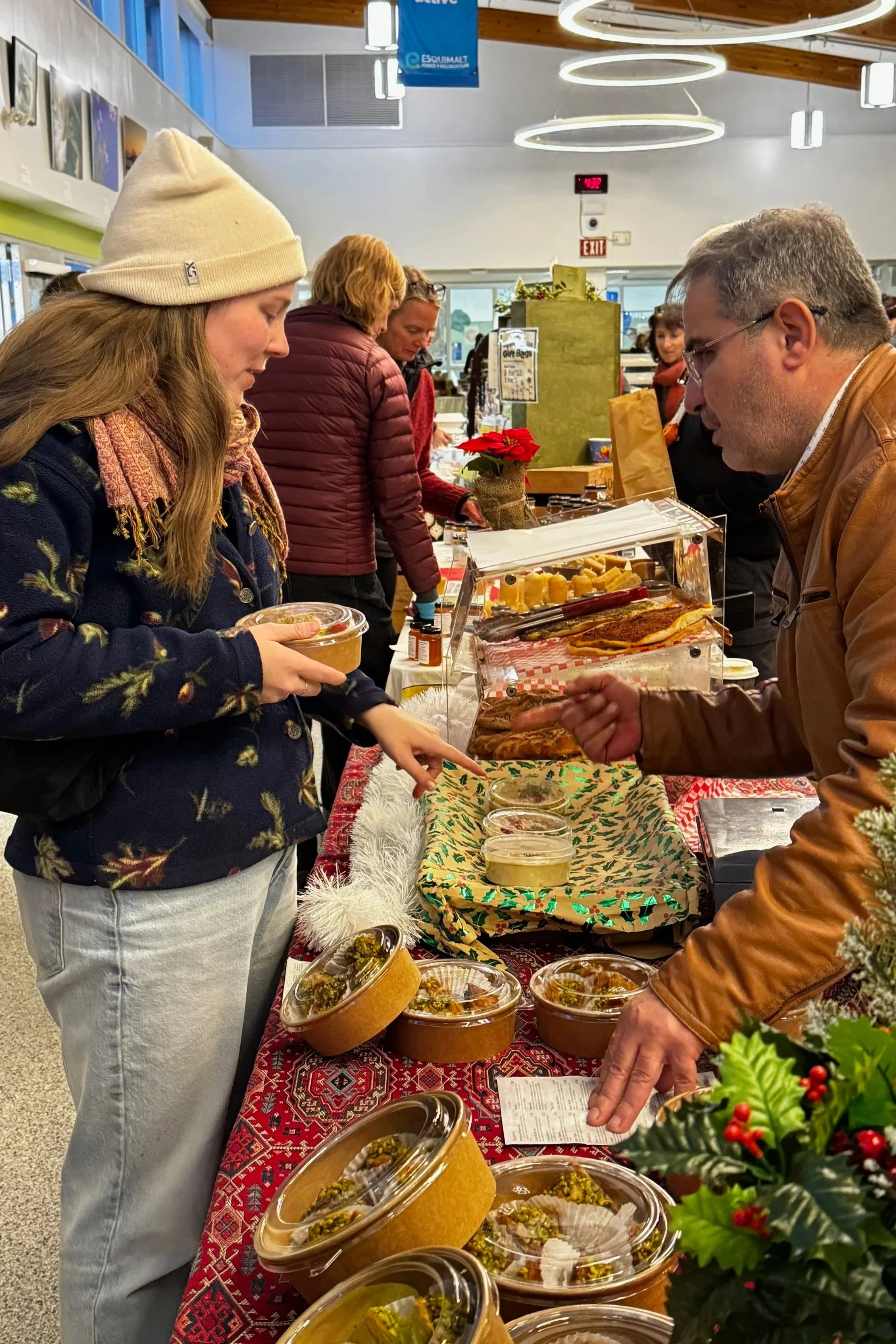 People shopping at a holiday-themed market table with food and festive decorations.