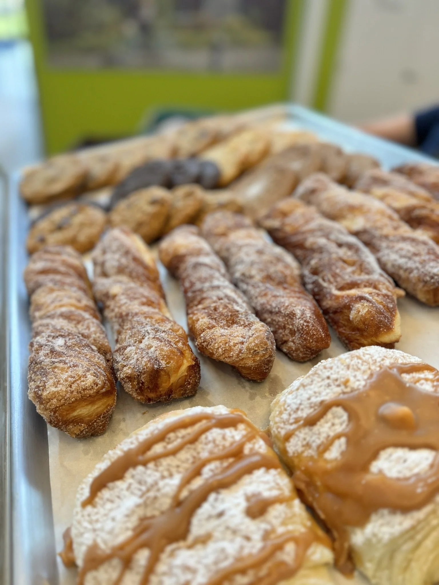 Assorted bakery pastries topped with caramel and powdered sugar, displayed on a tray.