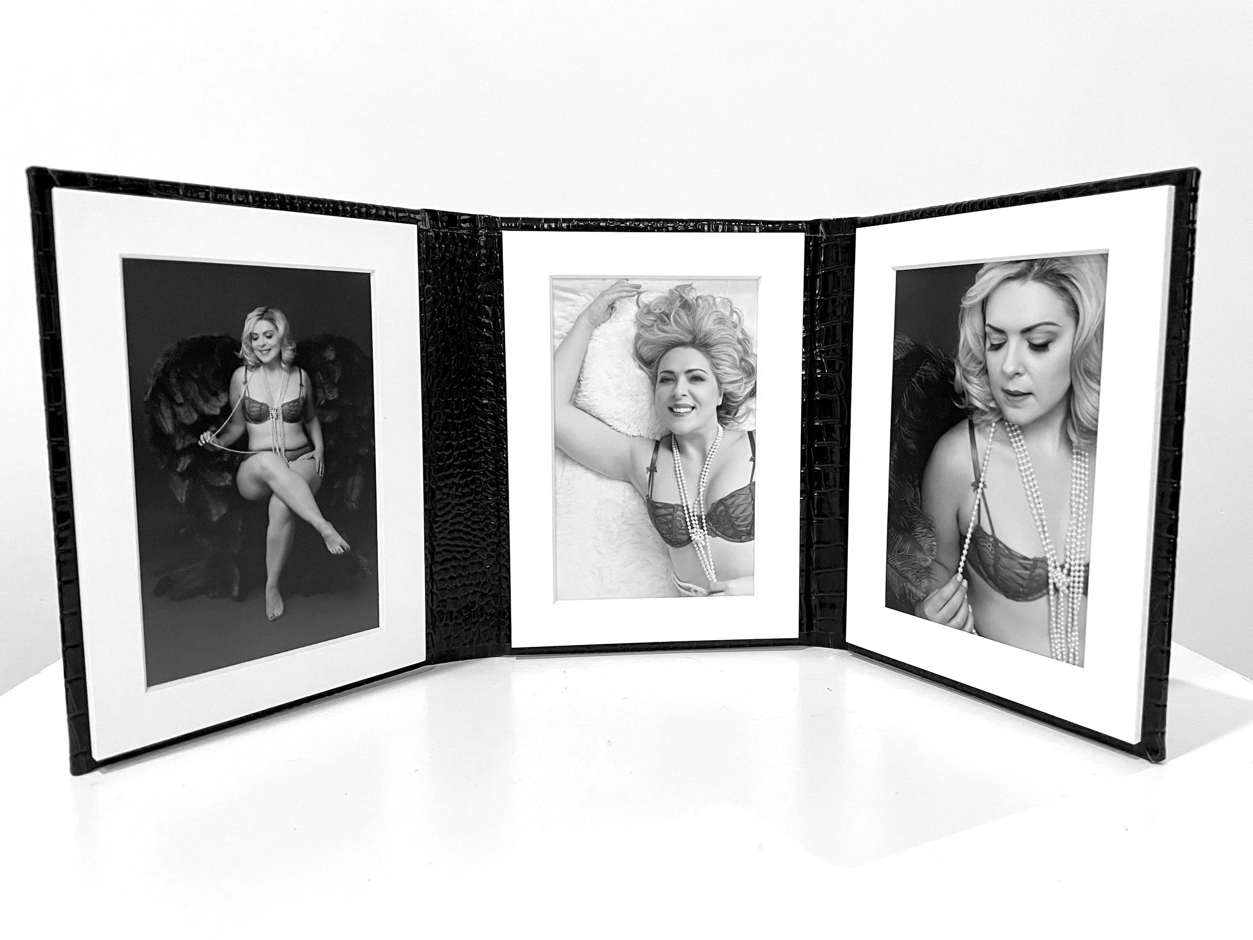 A tri-fold display with three black and white photographs of a woman in lingerie, accessorized with pearls, posed in different positions, on a white background.