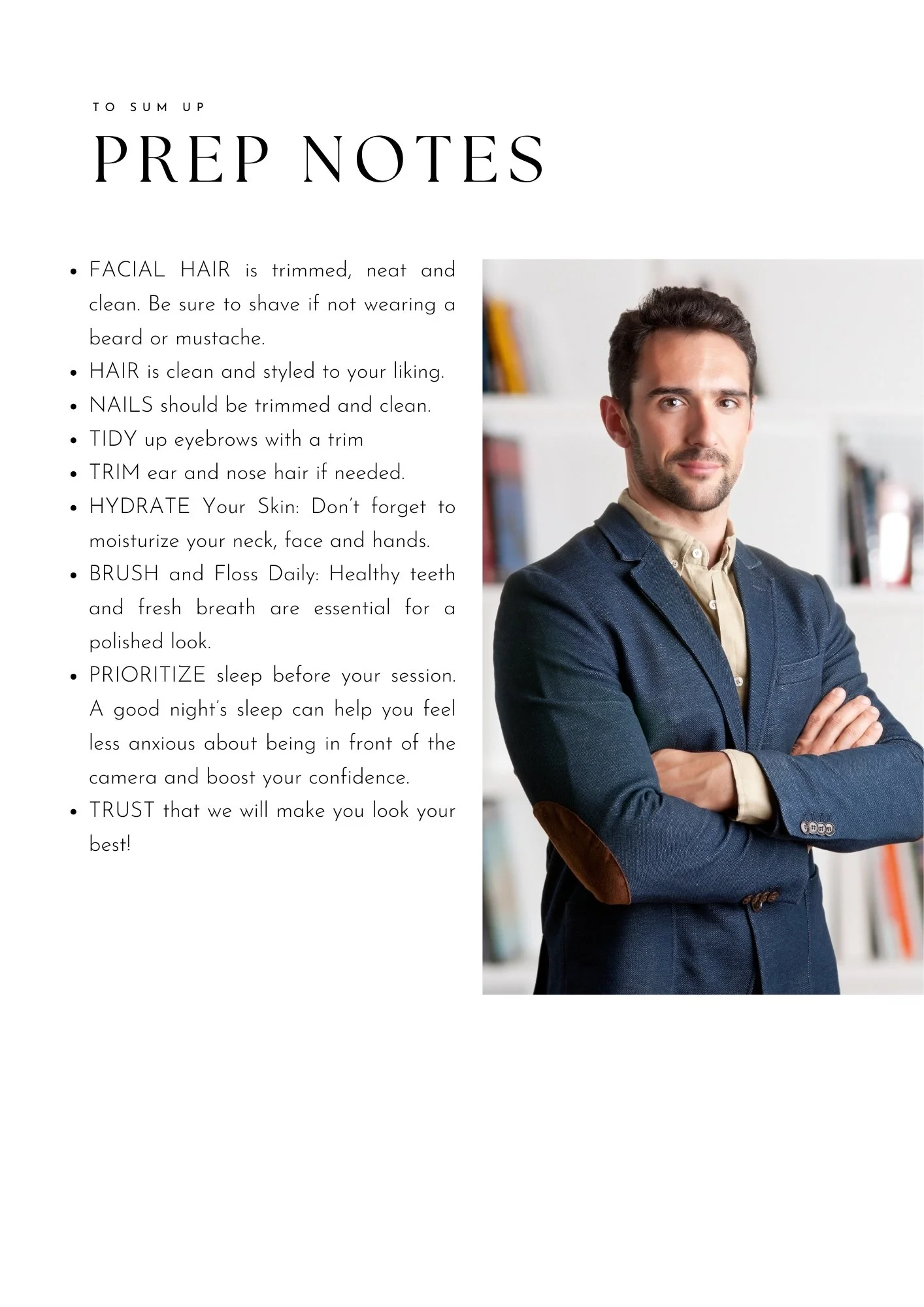 A man standing with arms crossed, wearing a blue blazer and beige shirt, in front of a white background with shelves.