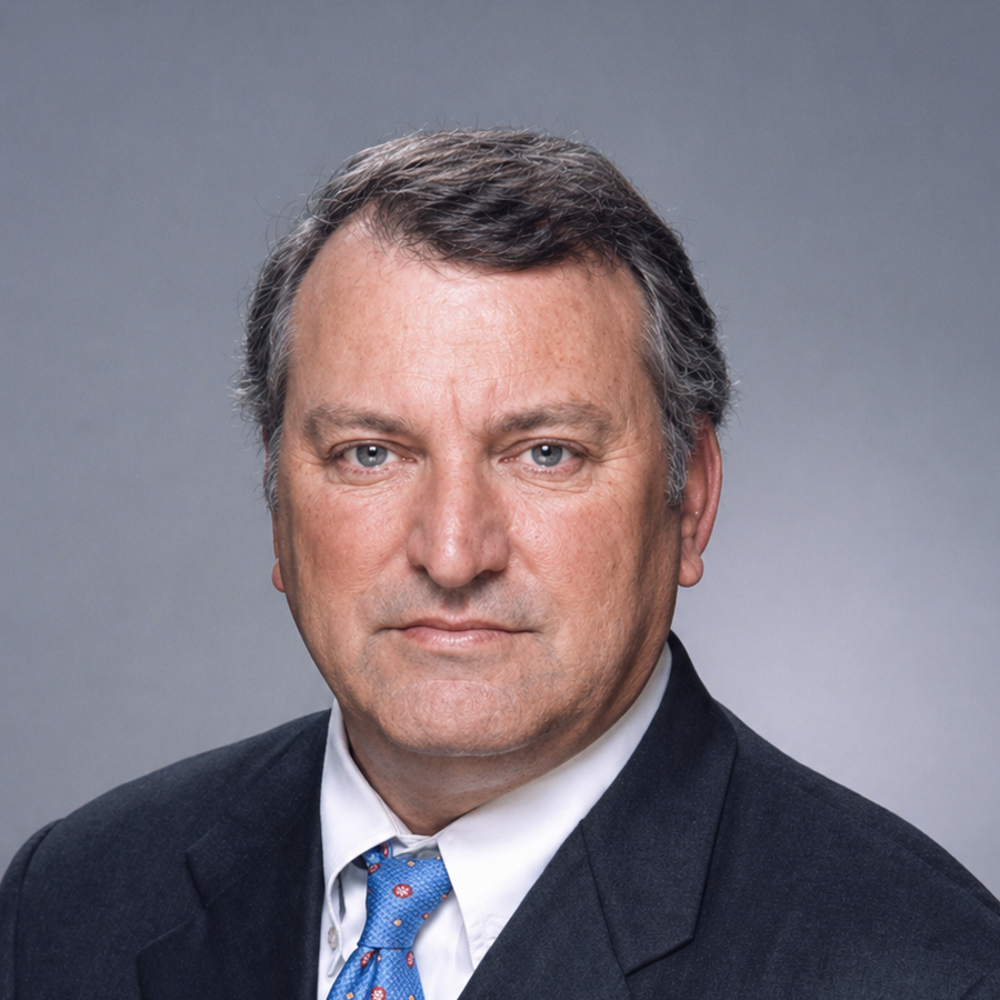 A portrait of a smiling man with gray hair, wearing a white collared