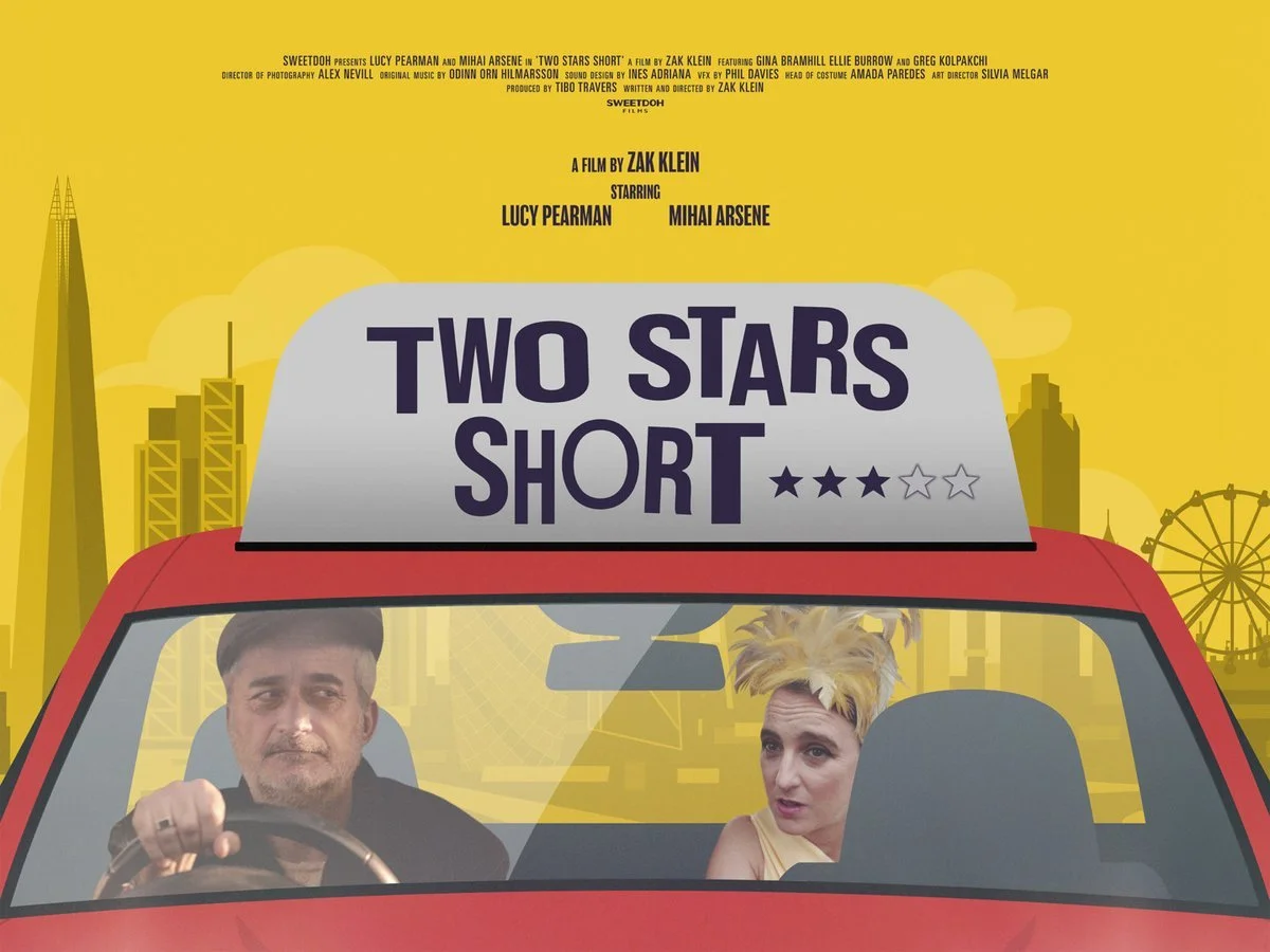 Movie poster for 'Two Stars Short' with a yellow background, featuring a red car with two characters inside, a man with dark hair driving and a woman with blonde hair in the passenger seat, and cityscape in the background.