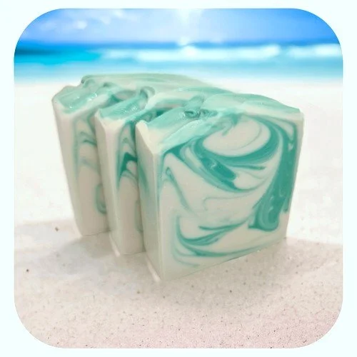 Handmade Montego Bay soap with aqua swirl on sandy beach background with ocean view