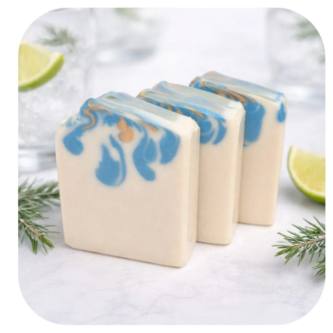 Handmade gin and tonic soap with blue and gold swirls, styled with lime slices and rosemary on a light background