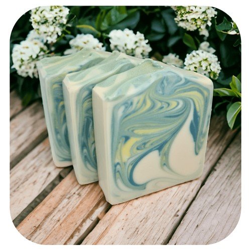 Handmade lemon myrtle soap with green and yellow swirl design on wooden surface with flowers