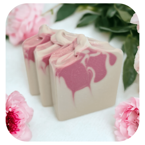 Handmade pink peony soap with soft pink swirl on white background with flowers