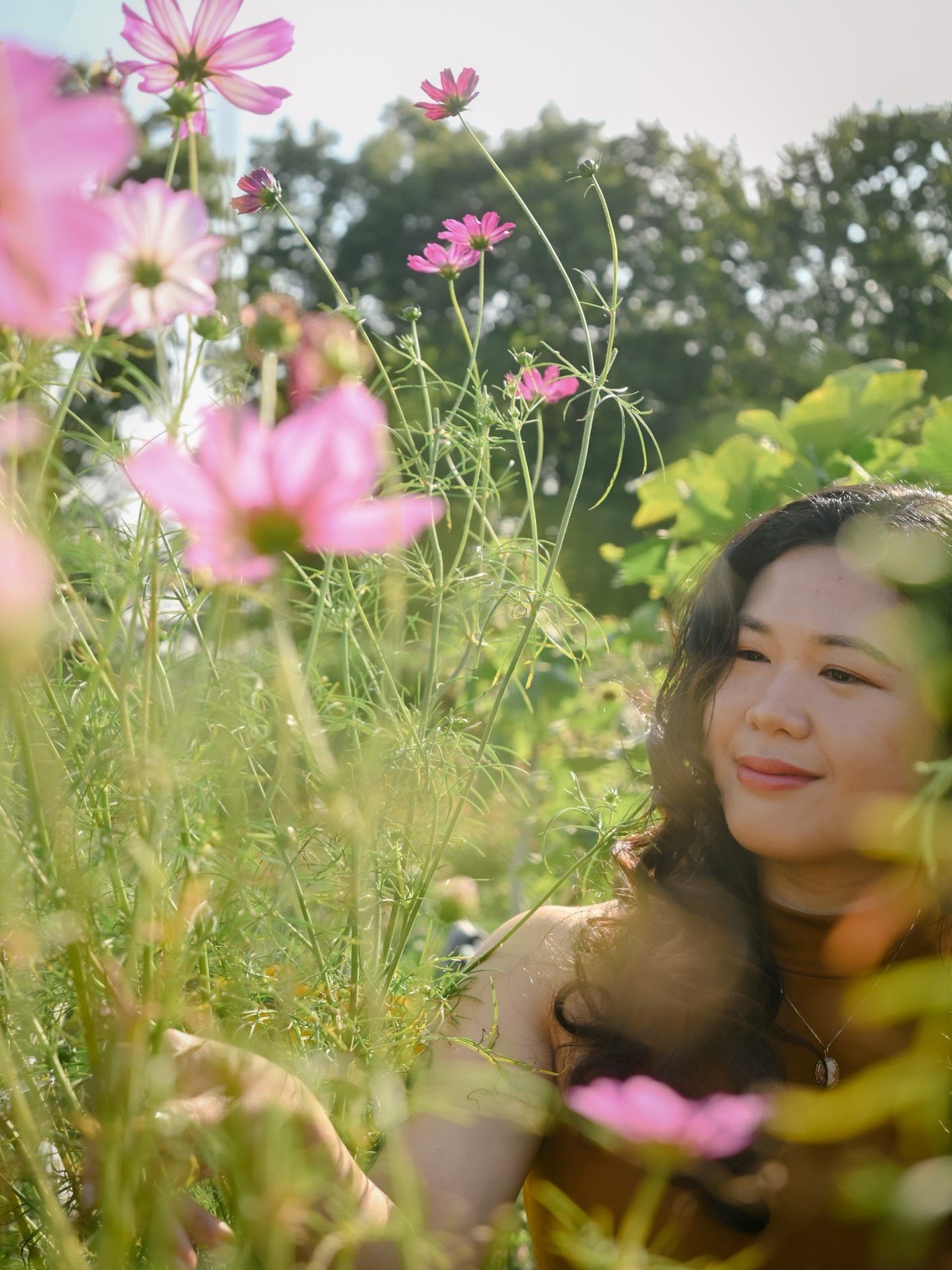 Cecille smiling in the garden while looking towards flowers