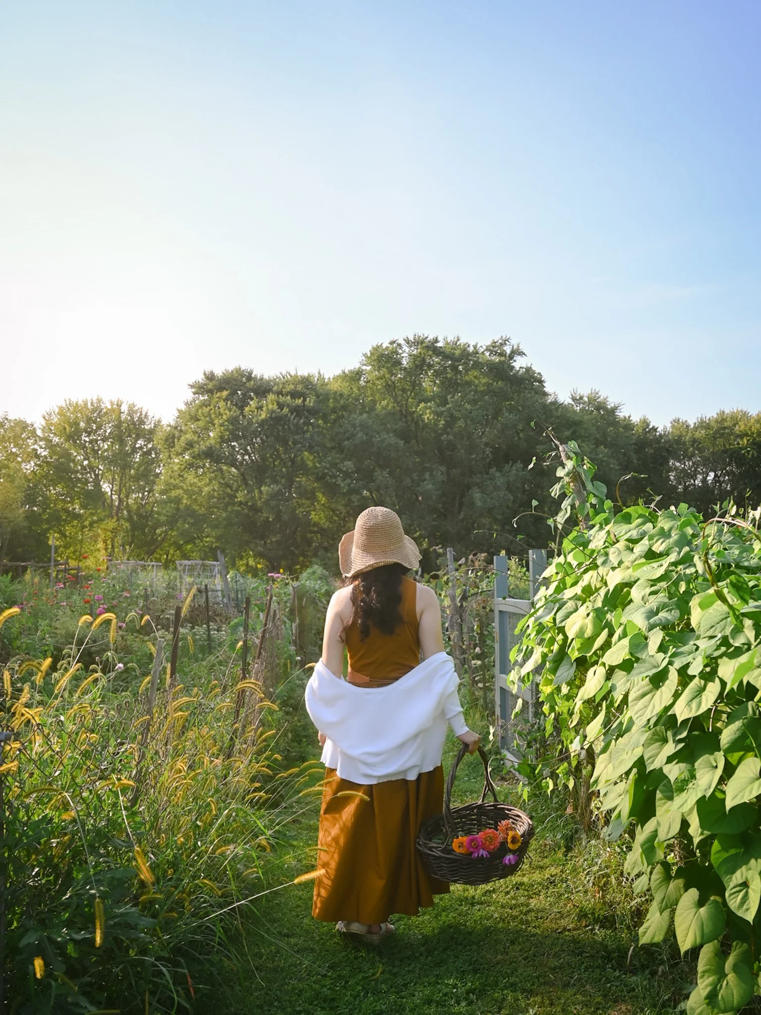 Cecille walking into a garden full of wildflowers garden with her back facing the camera