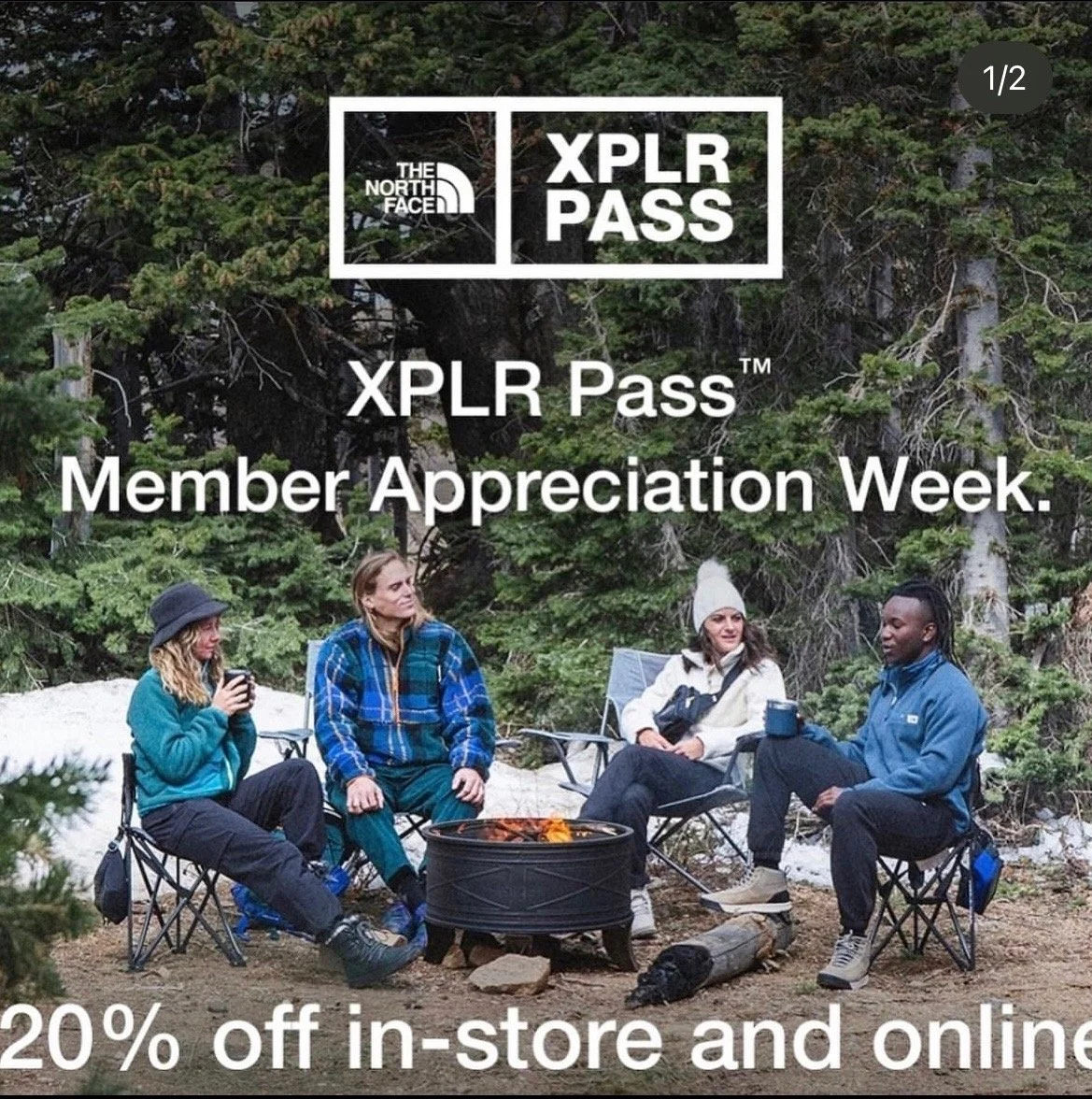 Four people sitting around a campfire in a forest, wearing outdoor clothing, with promotional text for The North Face's XPLR Pass Membership Appreciation Week, offering 20% off in-store and online.